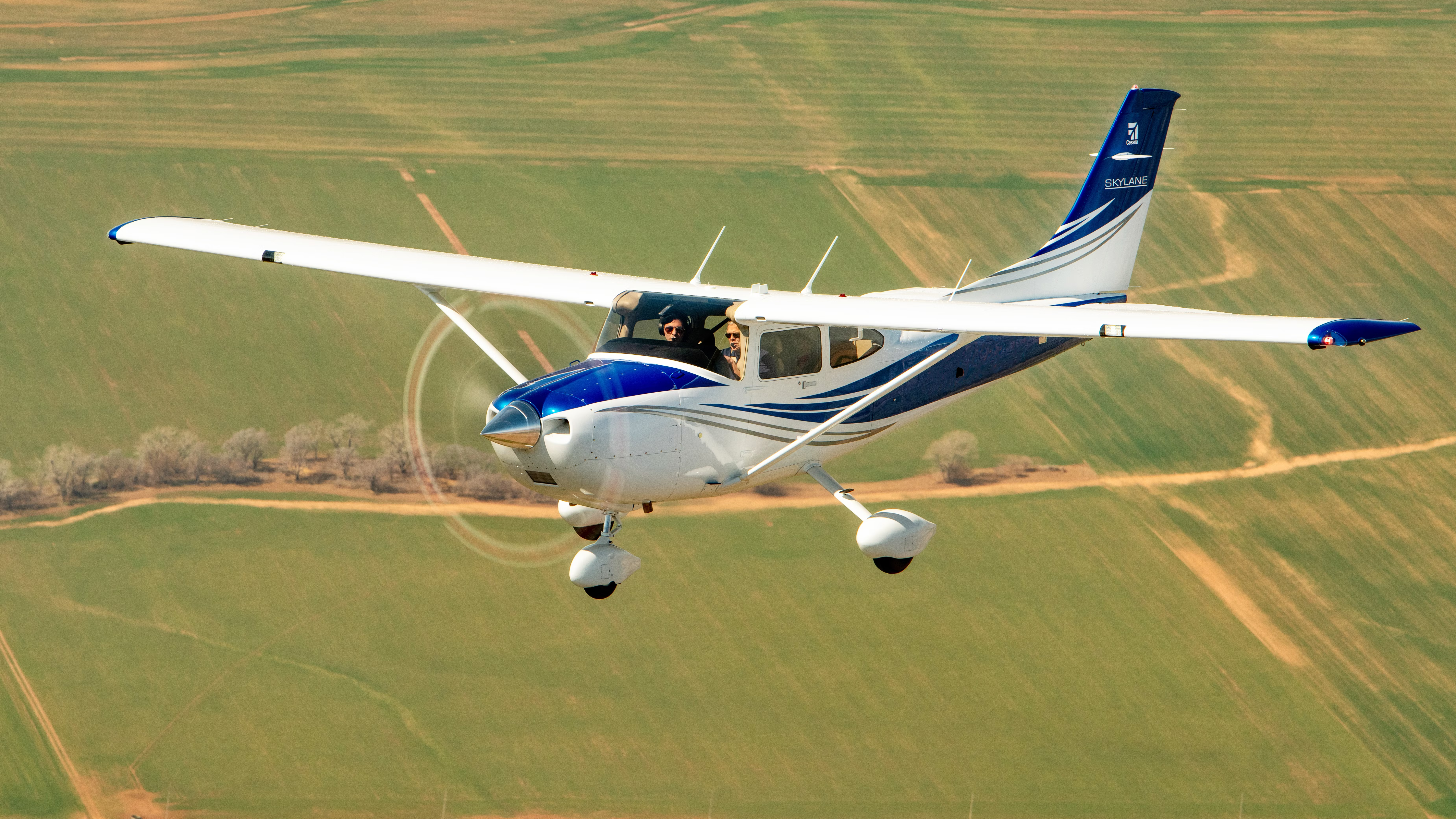 A Cessna 182 Skylane flying above a farm.