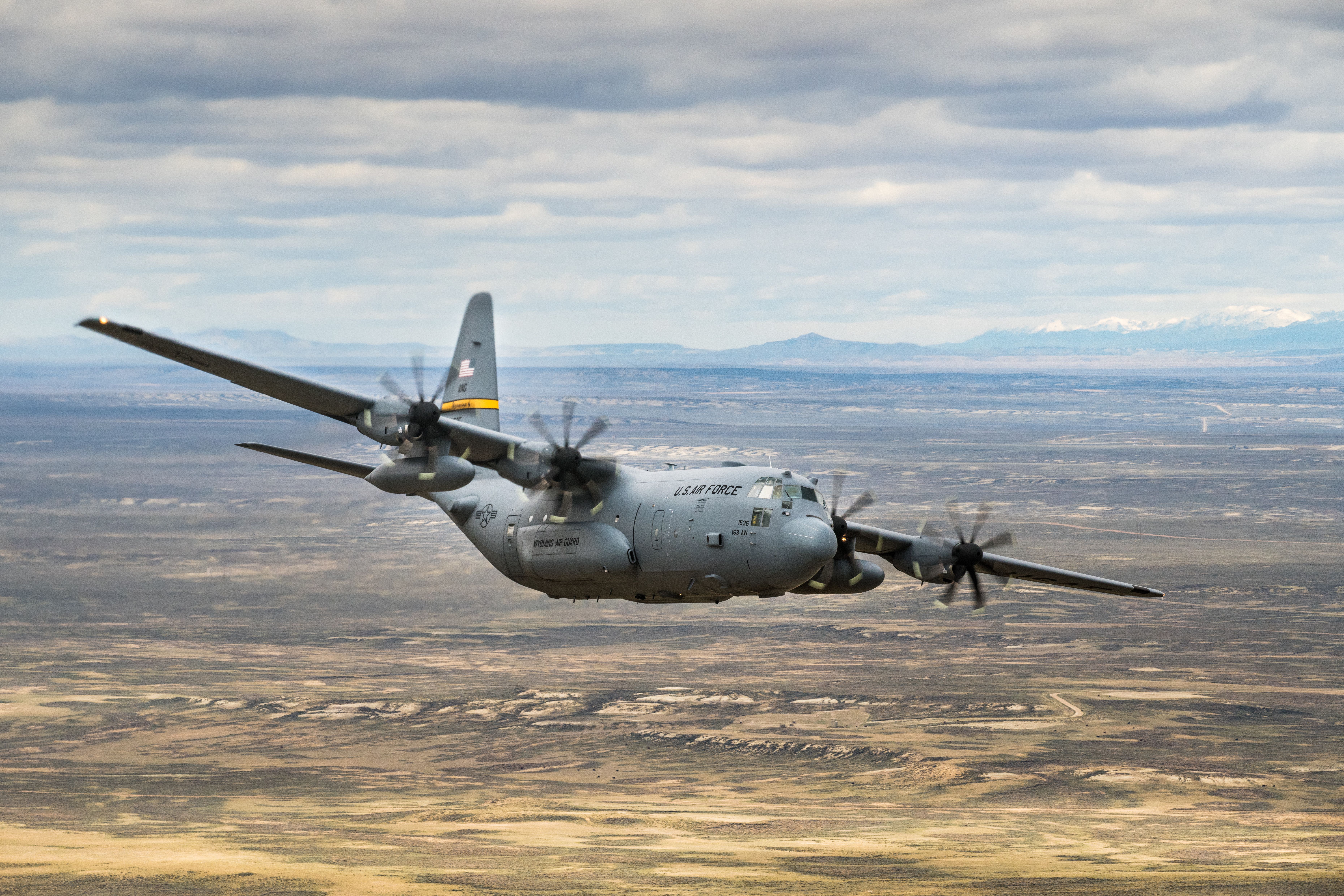 A USAF Lockheed C-130 Hercules flying over a desert.