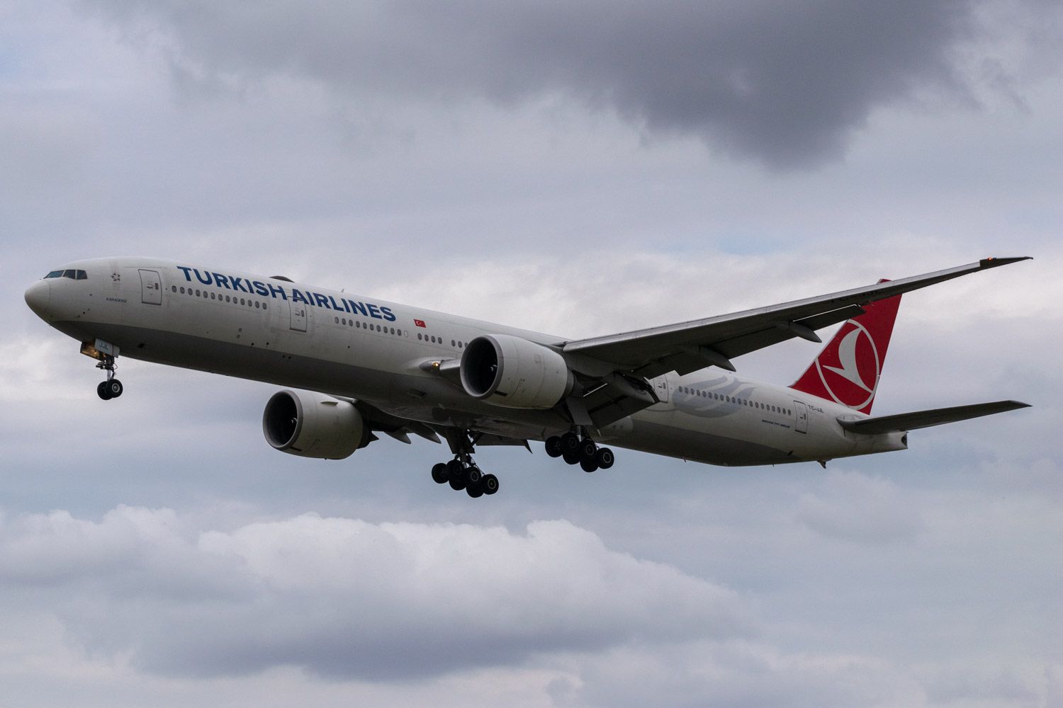 A Turkish Airlines Boeing 777-300ER Flying Under Gray Clouds.