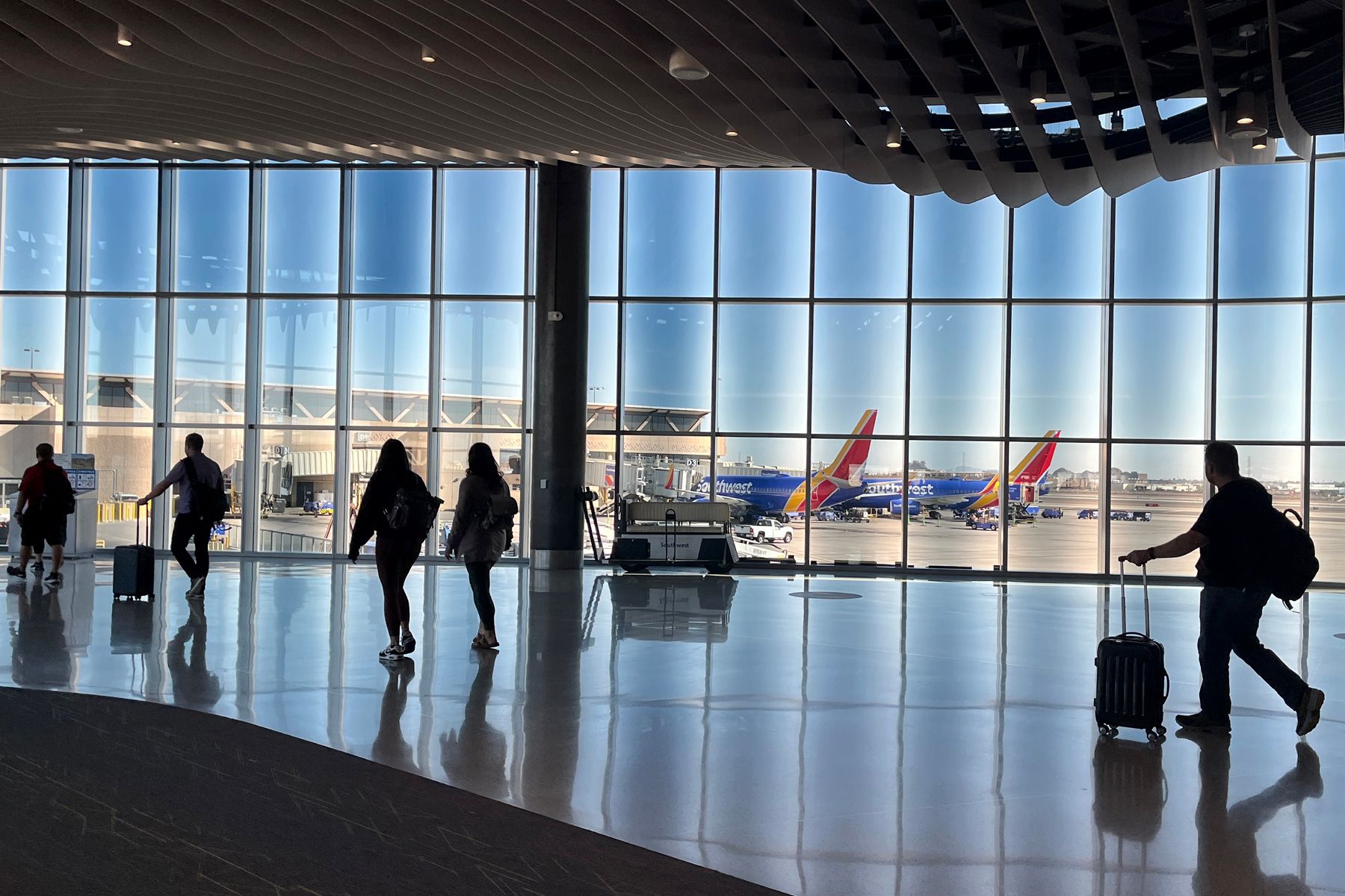 Passengers walking through an airport terminal, with multipl Southwest Airlines aircraft seen out the window.