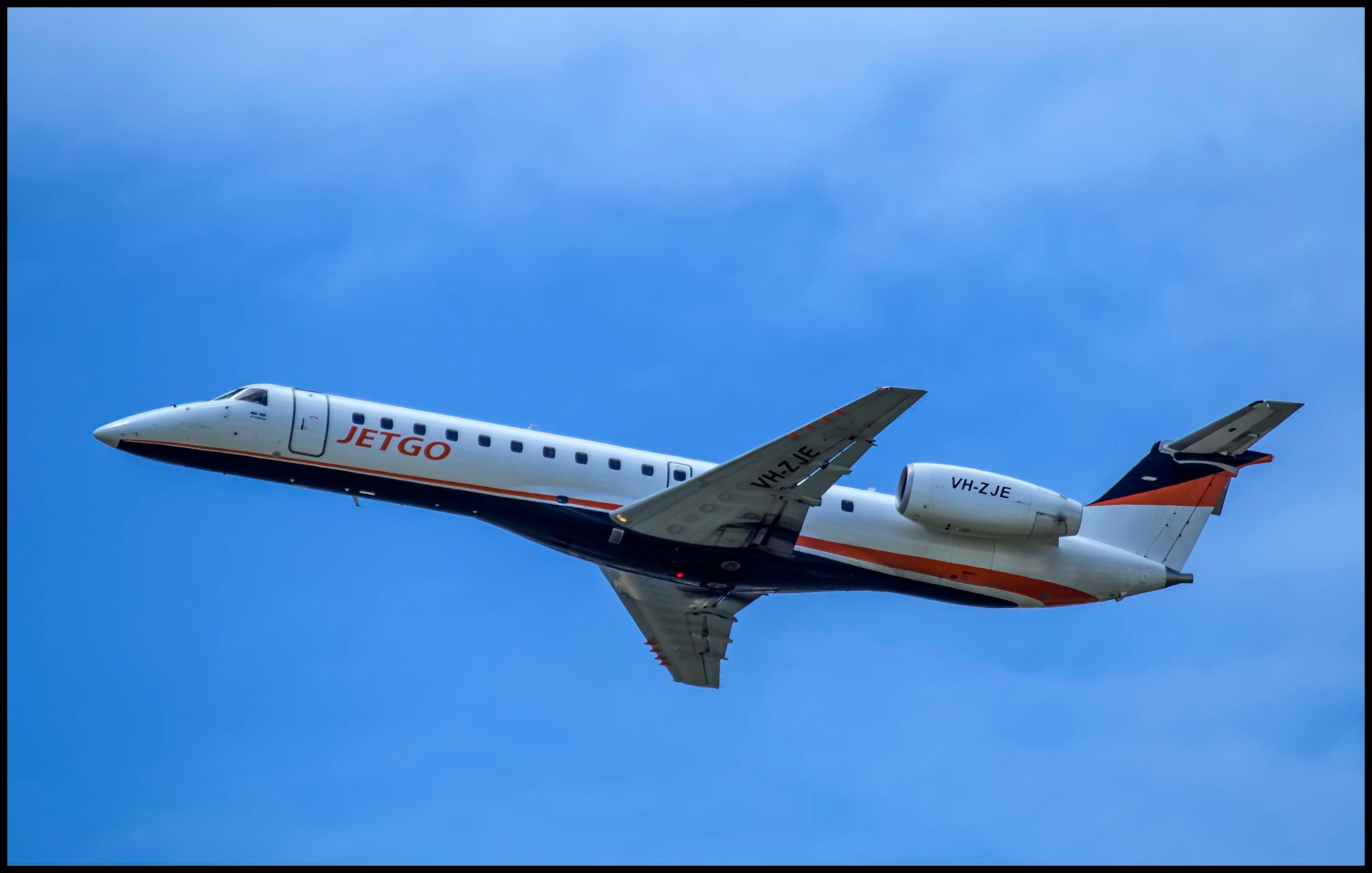 A JetGo Embraer jet flying in the sky.
