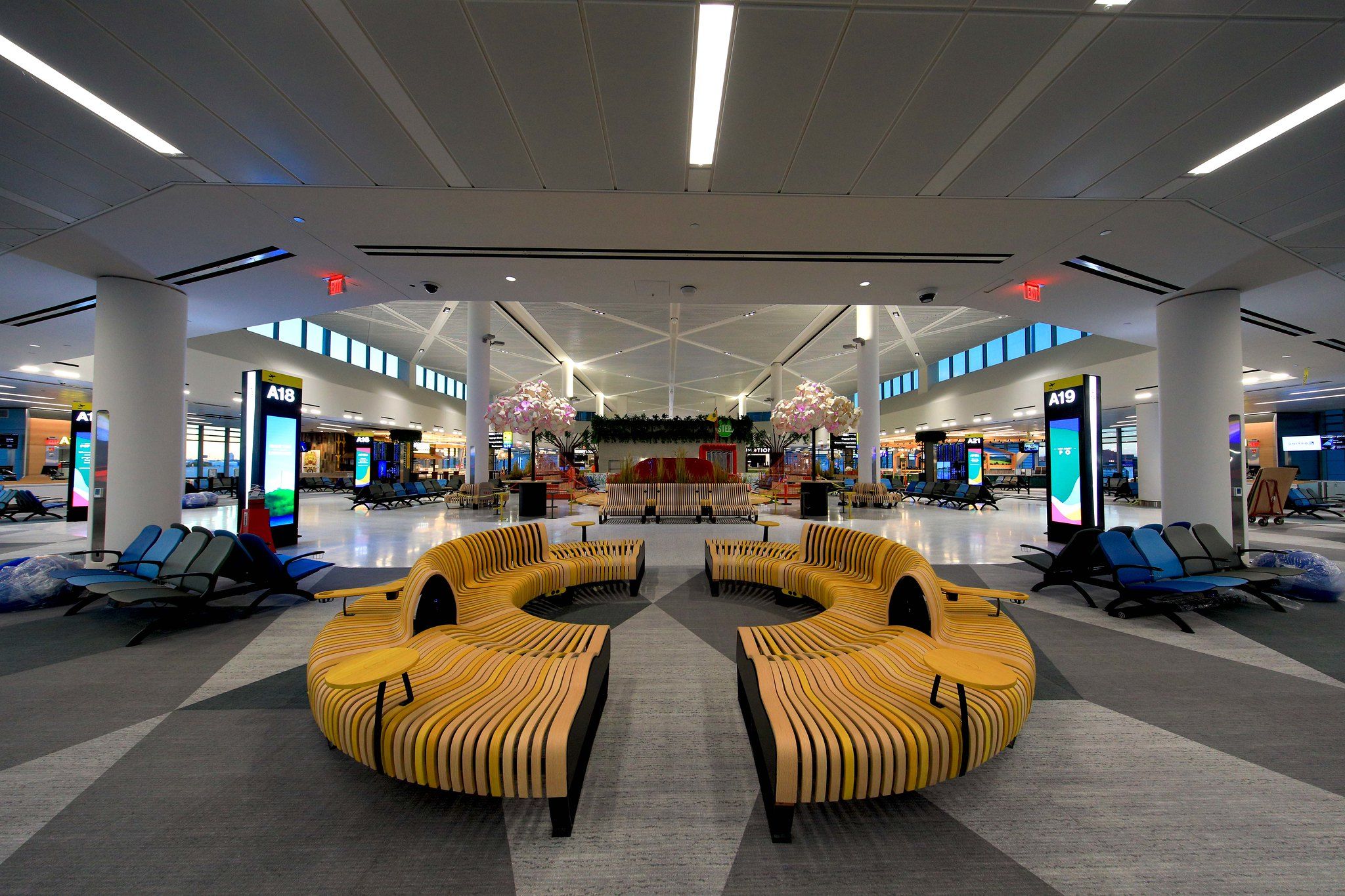 Interior of a terminal building with a circular yellow seating area and several lounge chairs.