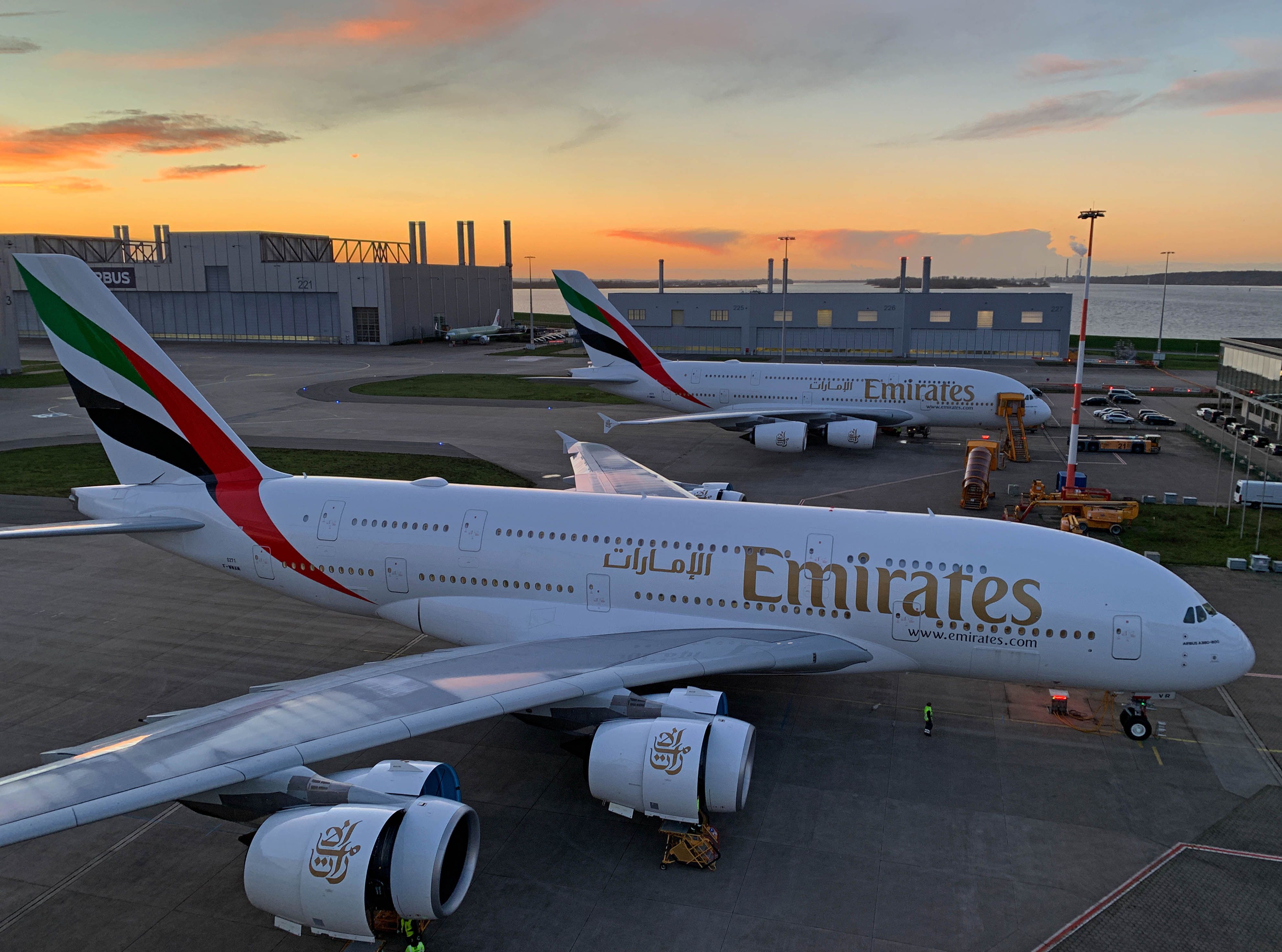 Two Emirates Airbus A380s Parked Under A Golden Sky.