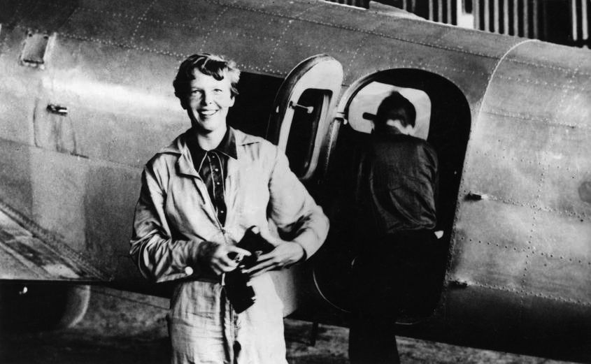 Amelia Earhart standing in front of an aircraft.