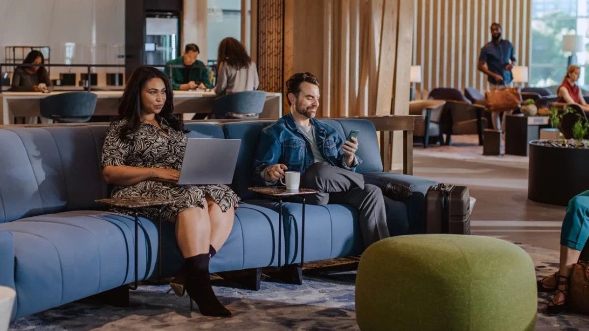 Several passengers sitting in an American Airlines Admirals Club lounge.