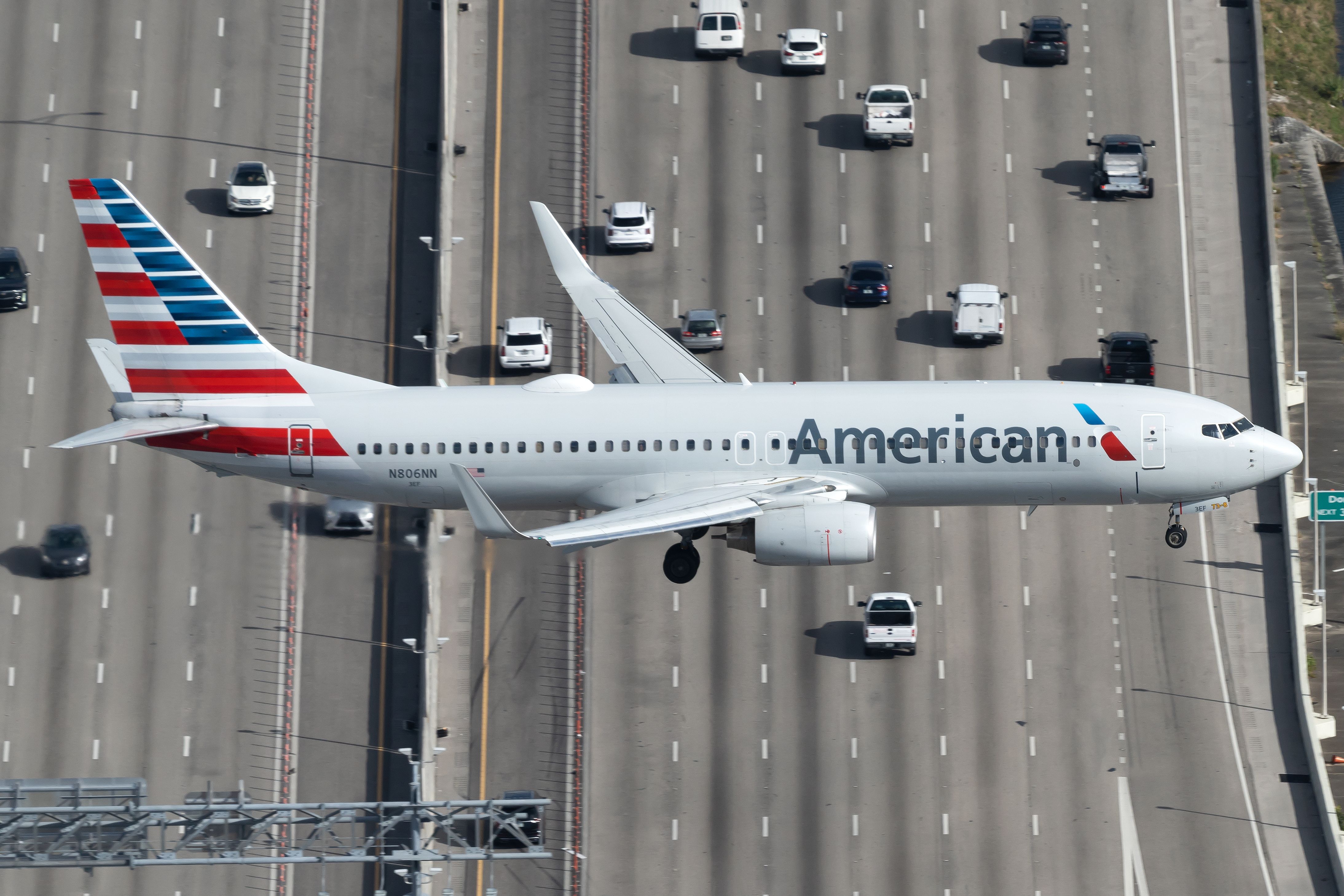 An American Airlines Boeing 737-800 flying over a highway just before landing.