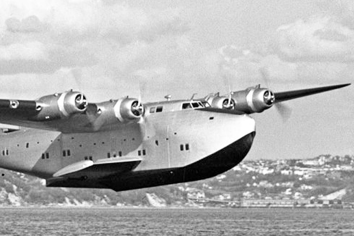 A Boeing 314 Clipper flying just above a large body of water.