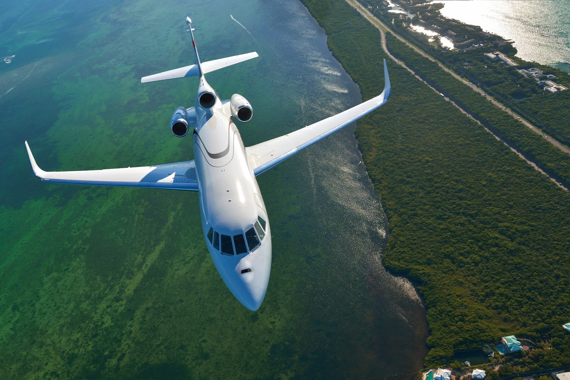 A Dassault Falcon 900LX flying over a coastline.