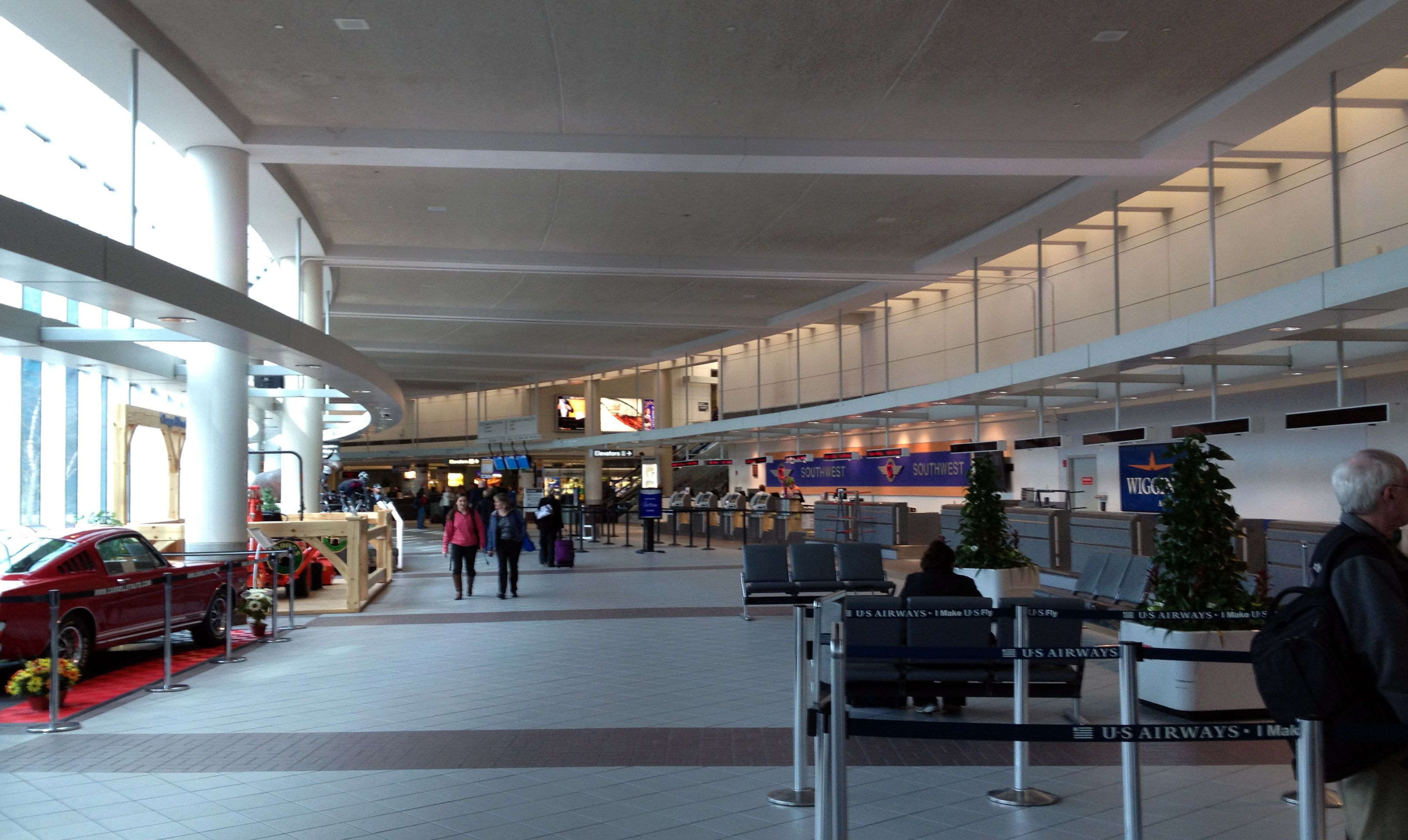 Interior of an airport terminal with passengers walking by check-in desks.