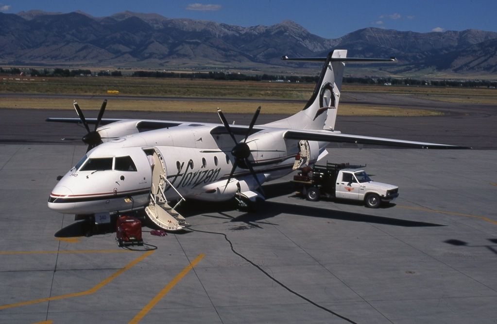 A Dornier 328 parked on an airport apron with a ground vehicle nearby.