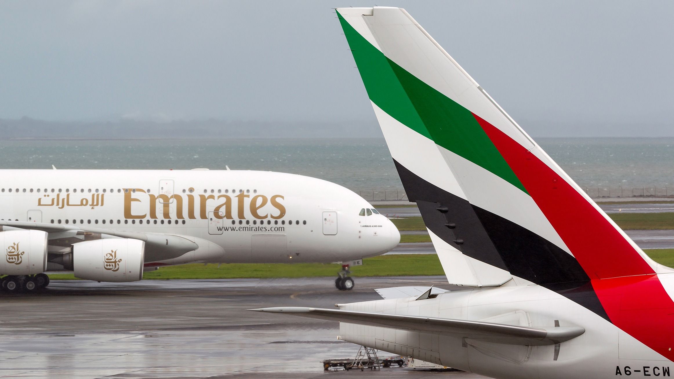 An Emirates Airbus A380 on a wet airport apron.