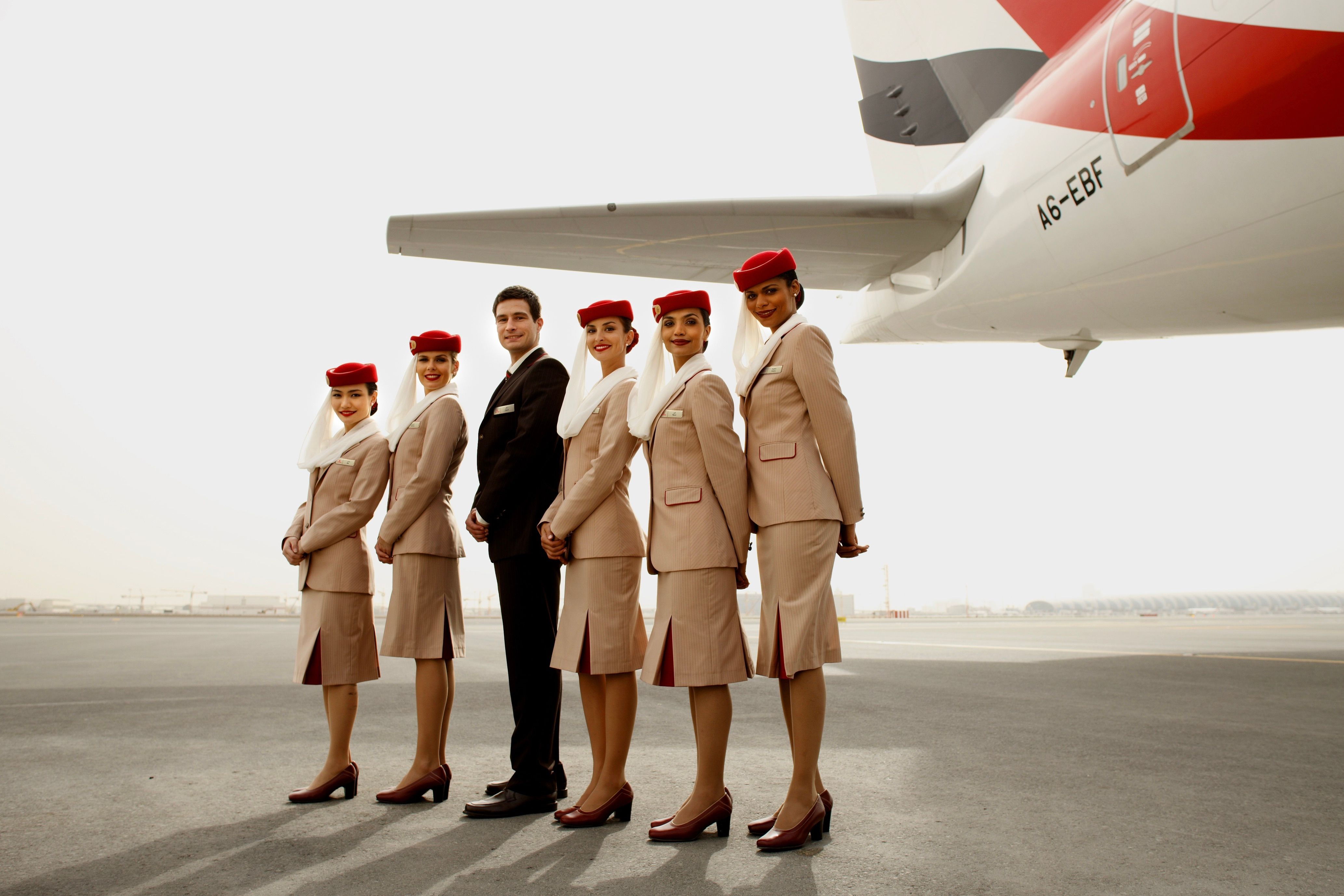 Several Emirates cabin crew standing next to an aircraft.