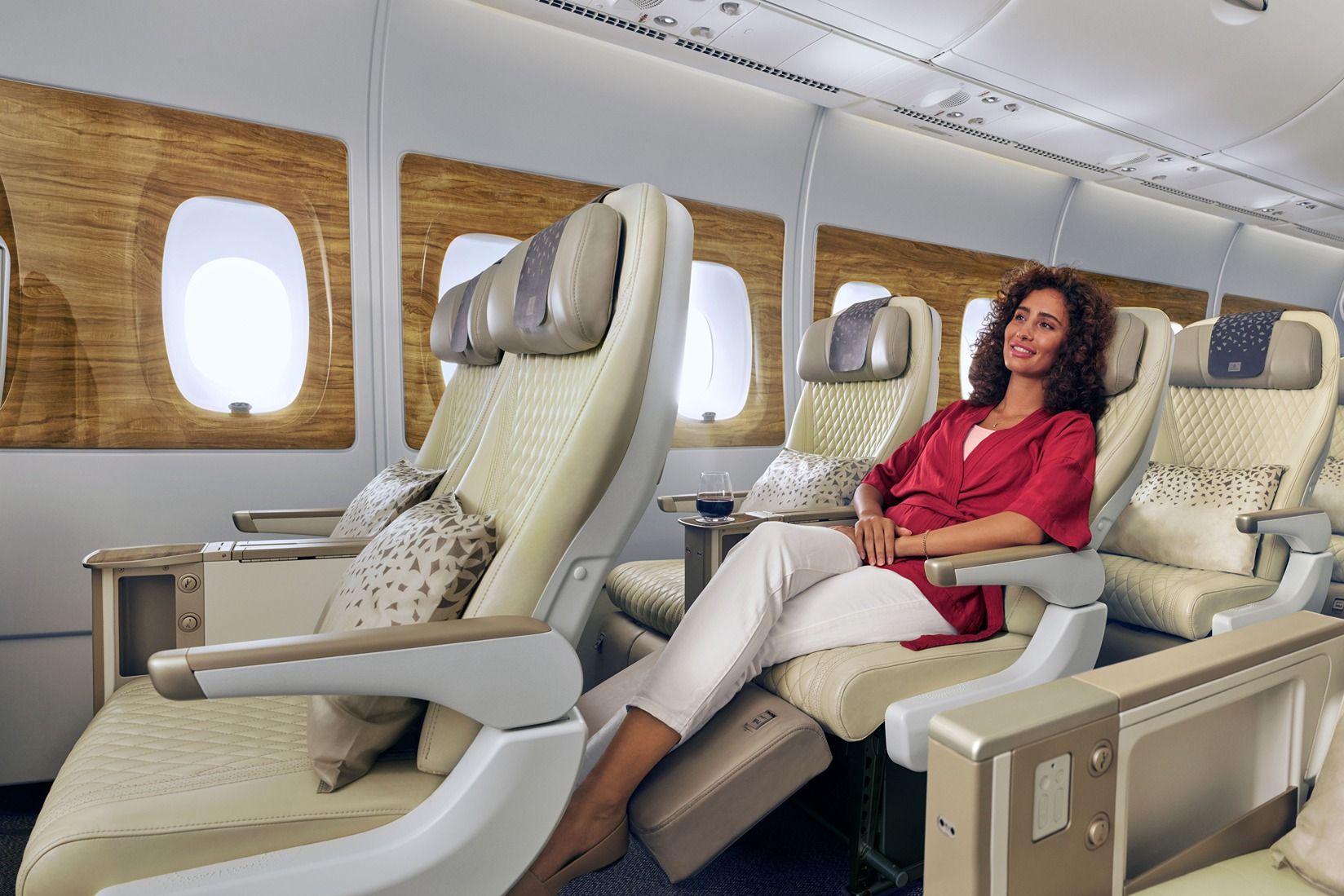 A passenger sitting in an Emirates premium economy seat.