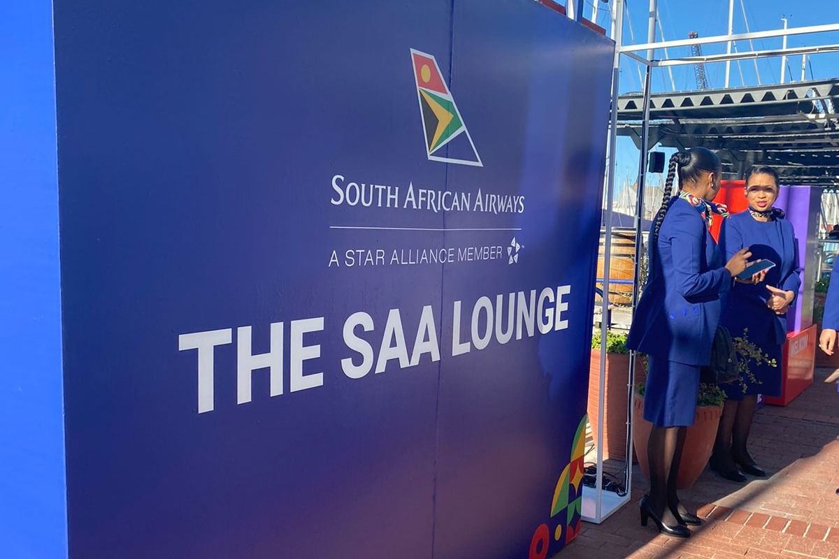 Two company representatives near a sign for the South African Airways new lounge.