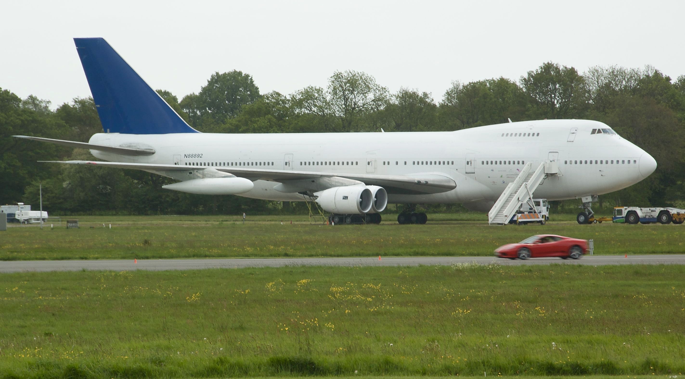 A White Boeing 747 with no livery parked at a small airfield.