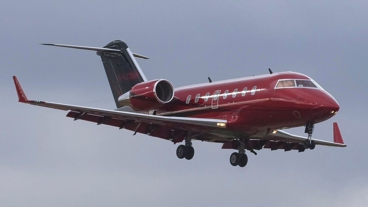 A red Bombardier Challenger 600 flying in the sky.