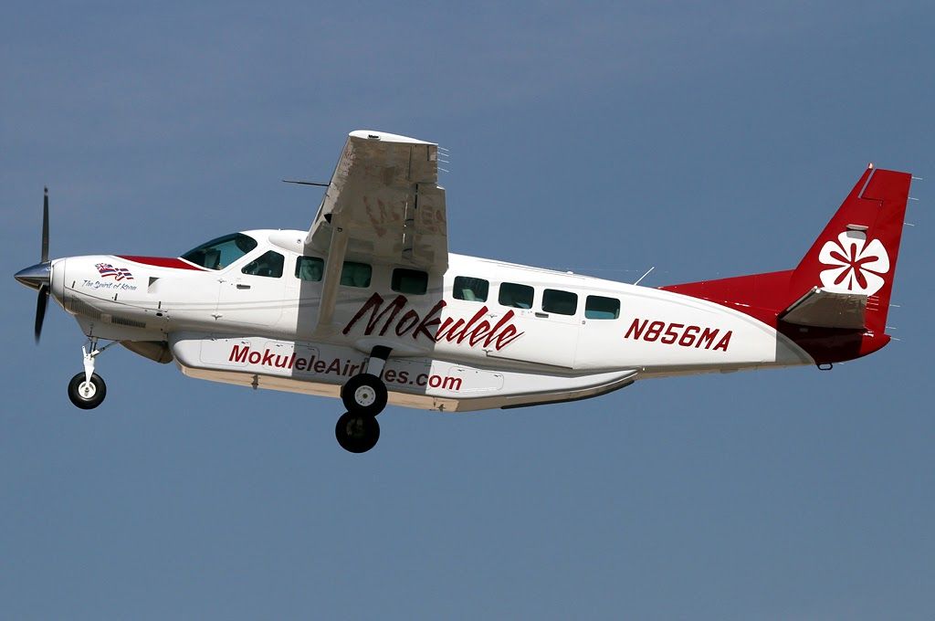 White Cessna aircraft with Mokulele painted in red on the side and a red tail flying through blue sky