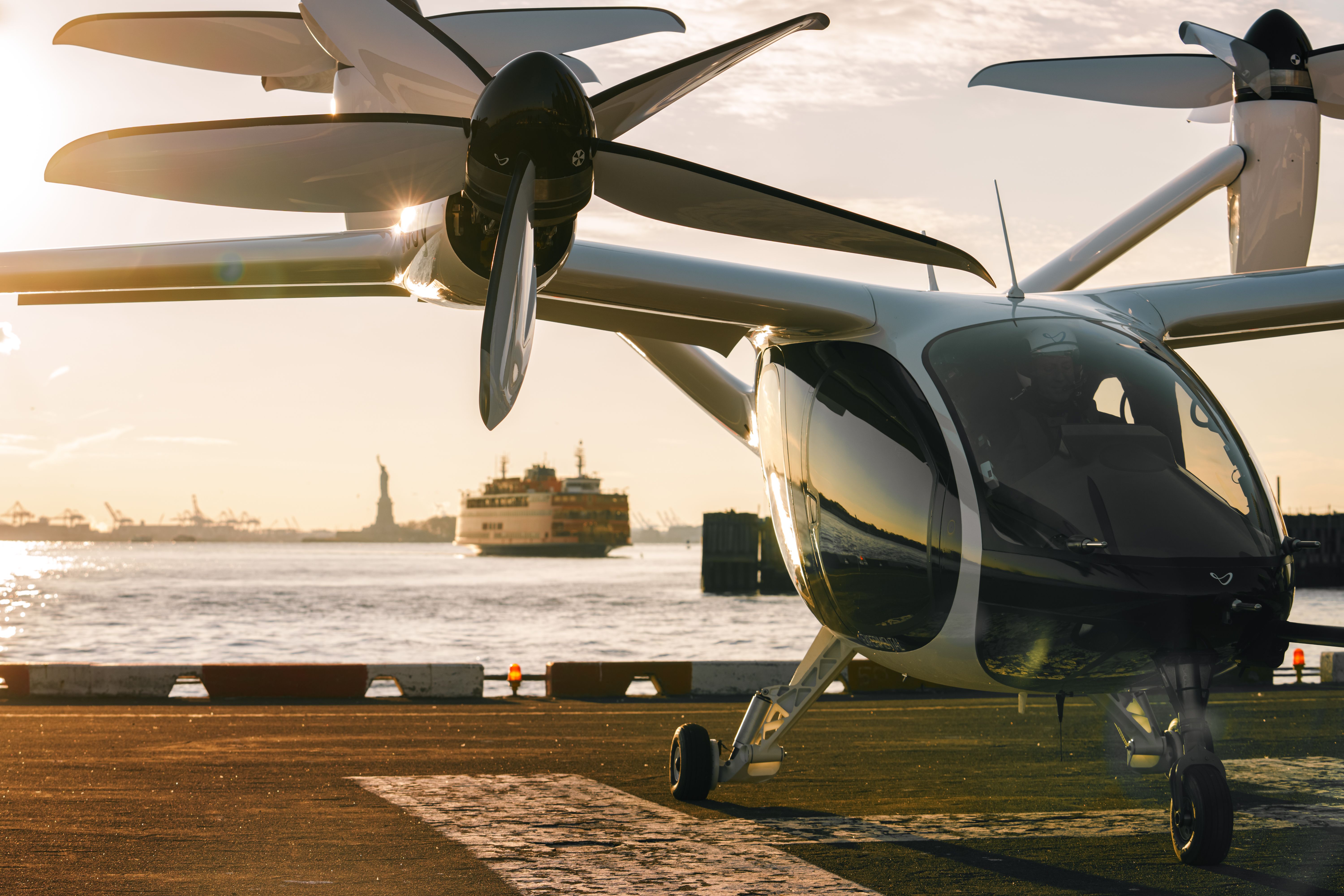 NYC_Joby-4 - Joby Aviation eVTOL on a New York City helipad with Staten Island Ferry & Statue of Liberty in background