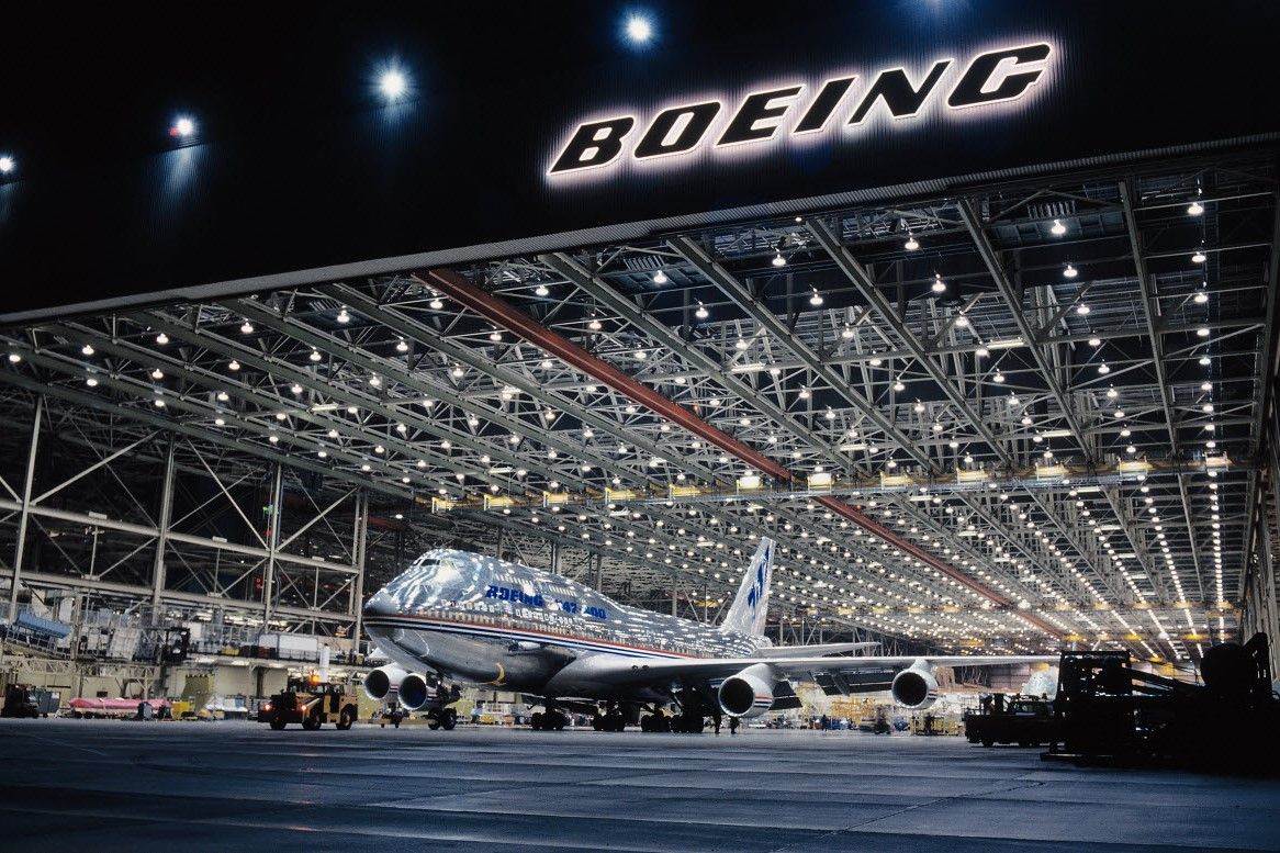 A silver Boeing 747 pakred in the Factory At Night.