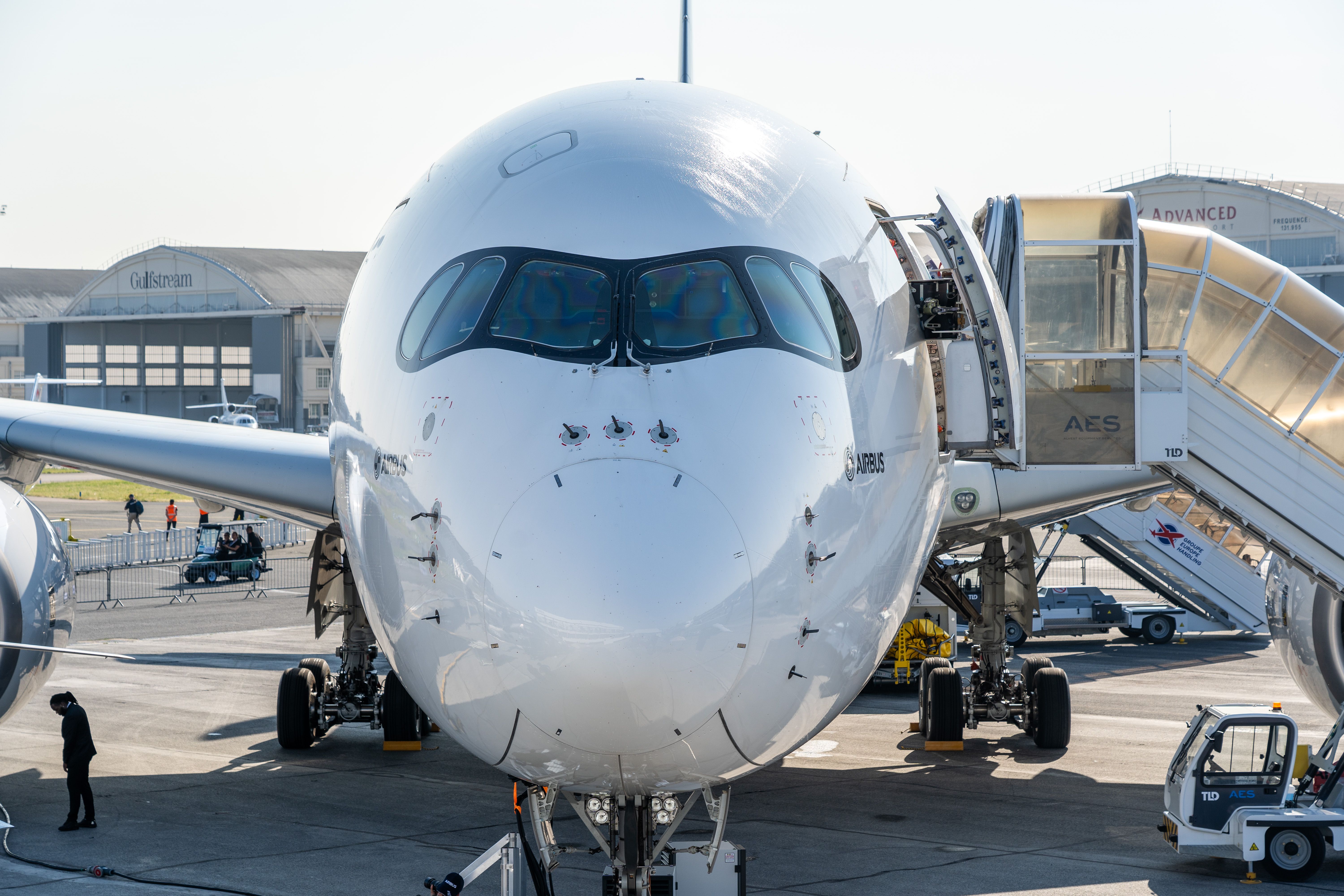 A Closeup of the nose of an Airbus A350 with air stairs parked next to it.