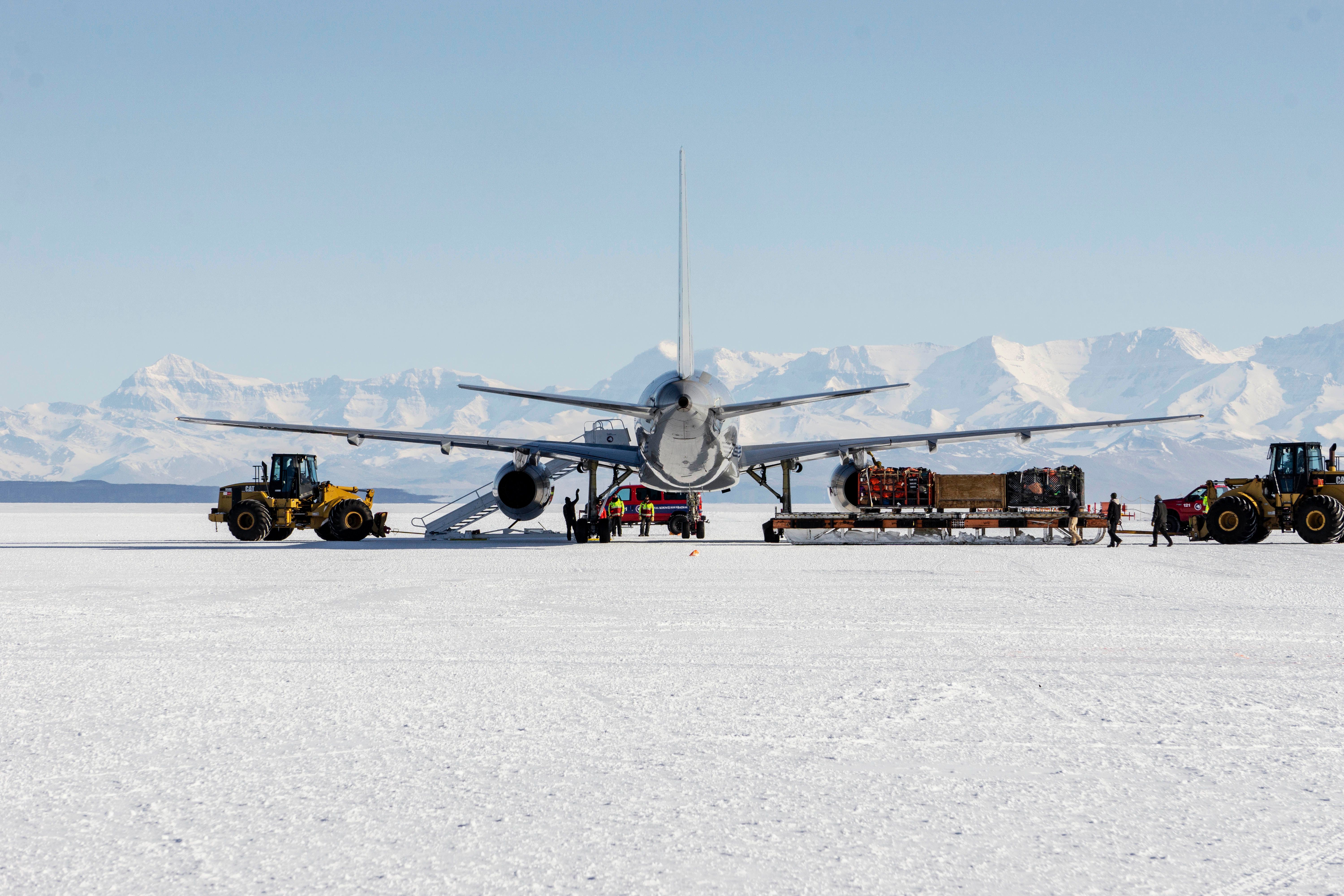 An aircraft parked on Antarctica, surrounded by maintenance vehicles.
