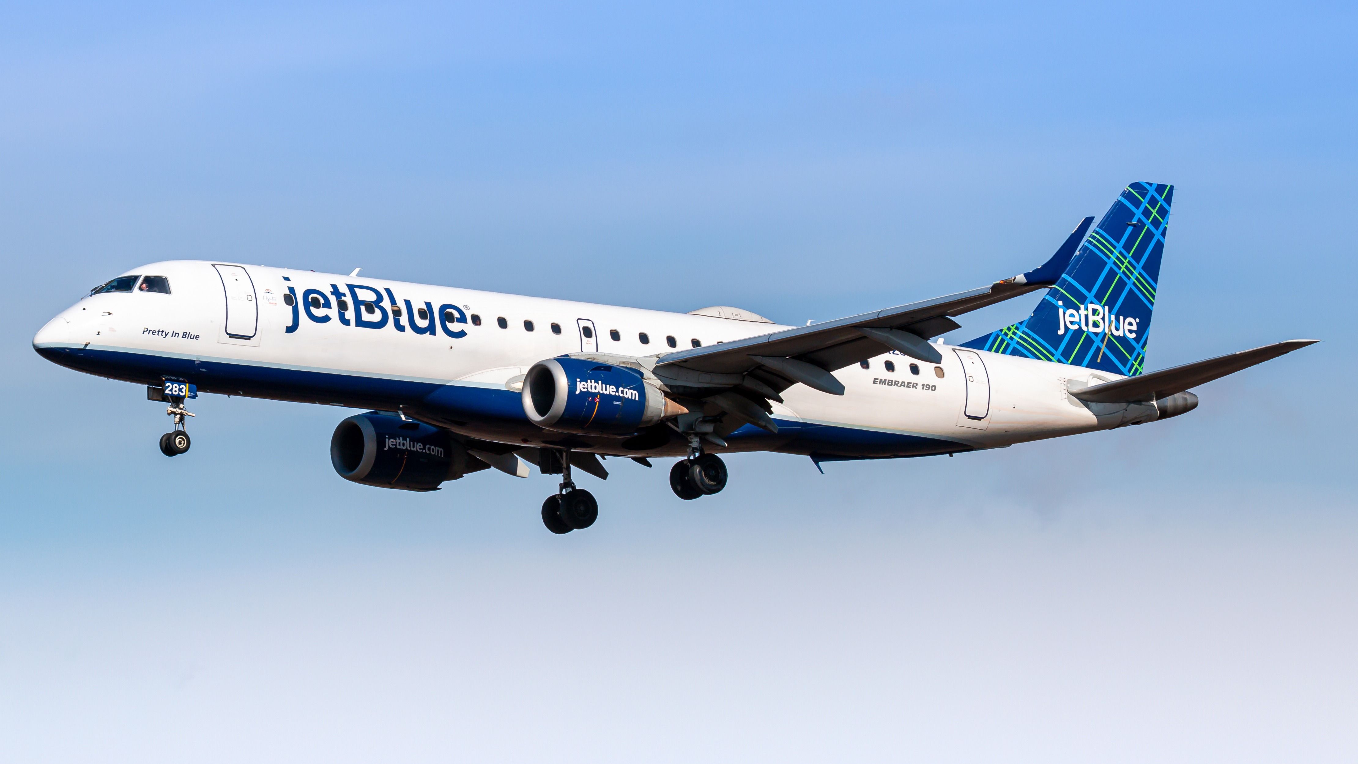 A JetBlue Embraer 190 flying in the sky.