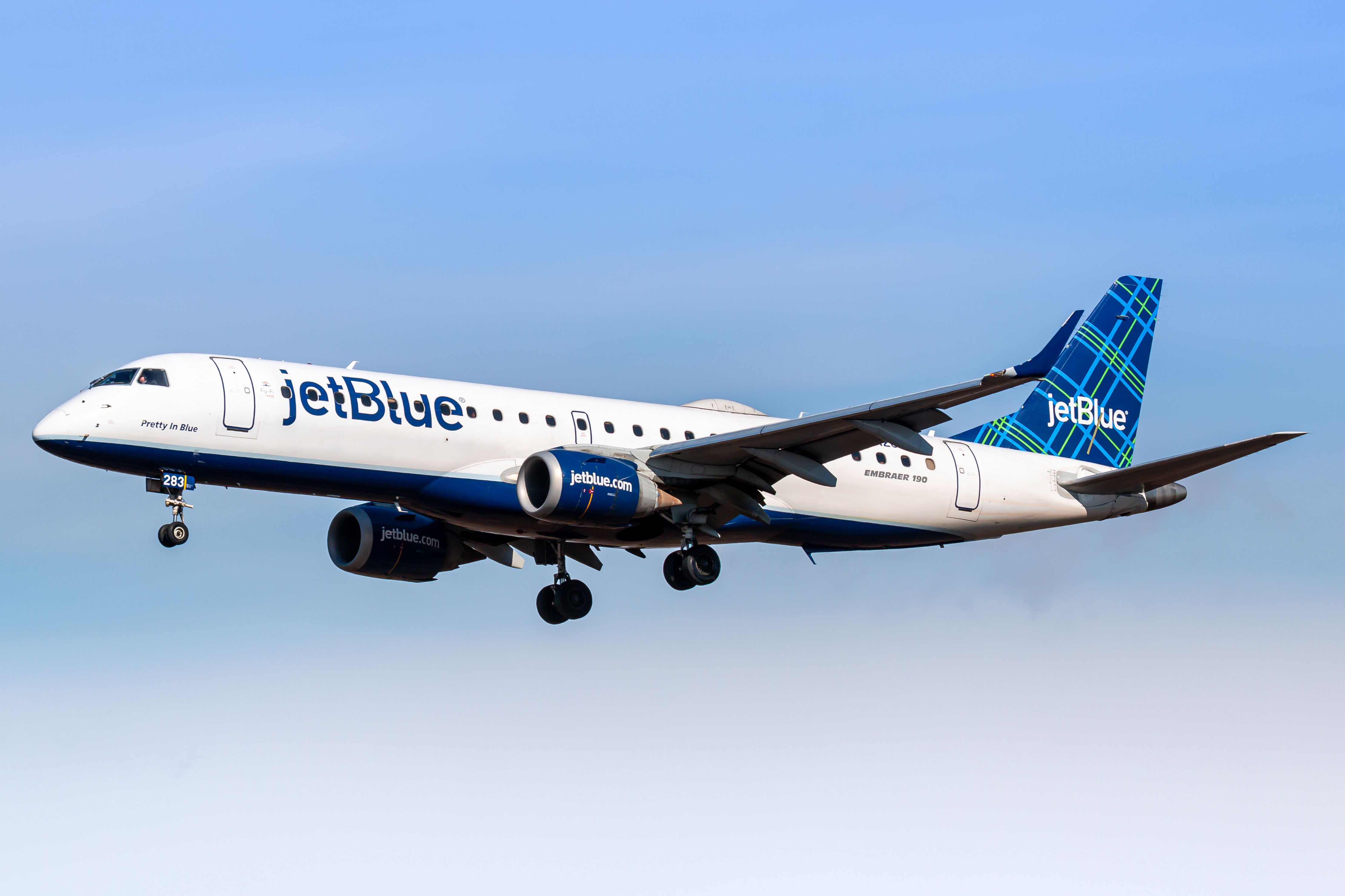 A Jetblue Embraer 190 flying in the sky.