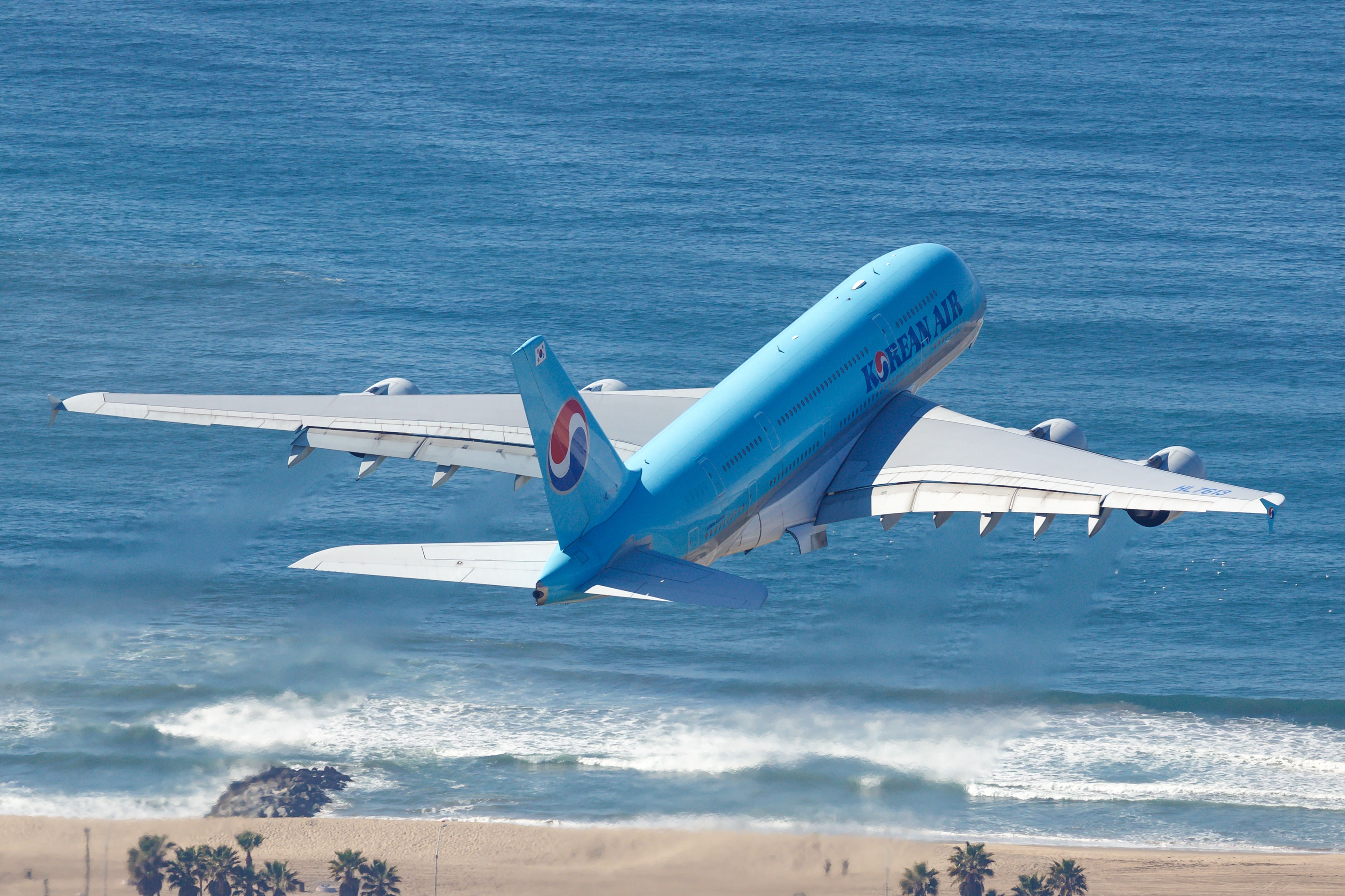 A Korean Air Airbus A380 taking off over a beach.