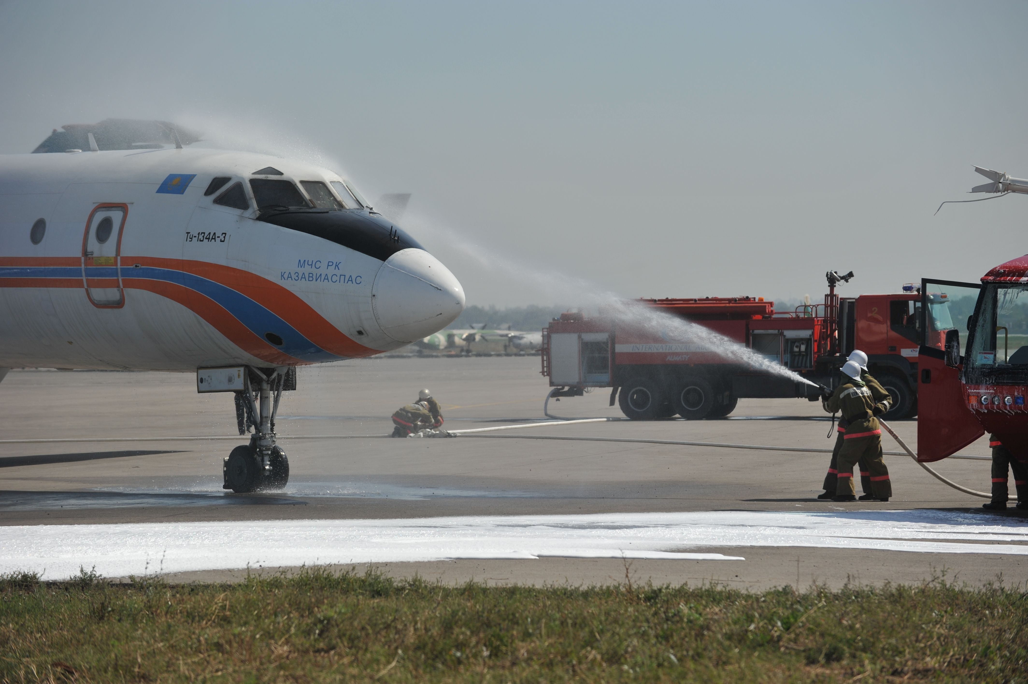 Firefighters Spraying An Aircraft's Nose With Water.