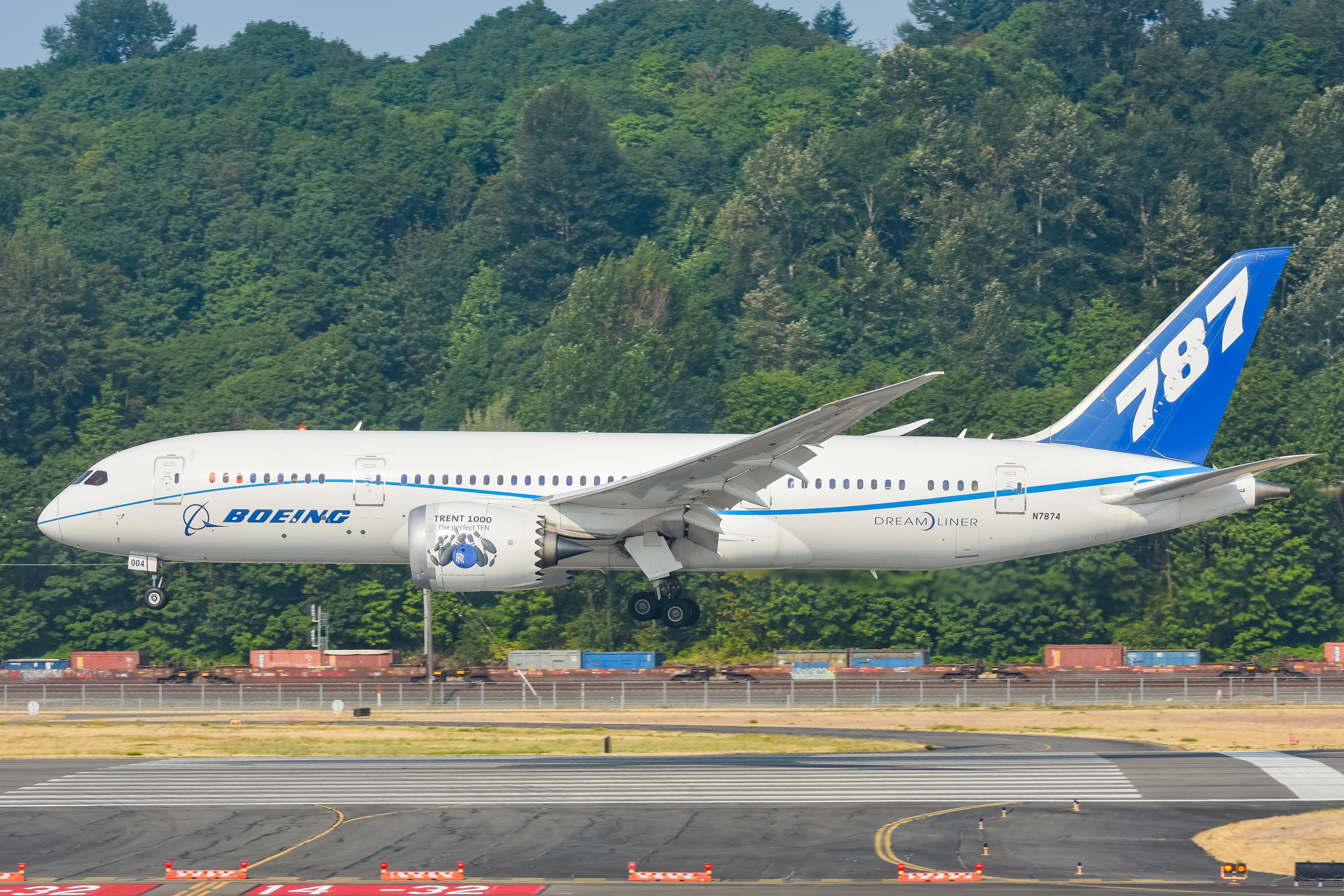 A Boeing 787 Dreamliner in house livery about to land on a runway.