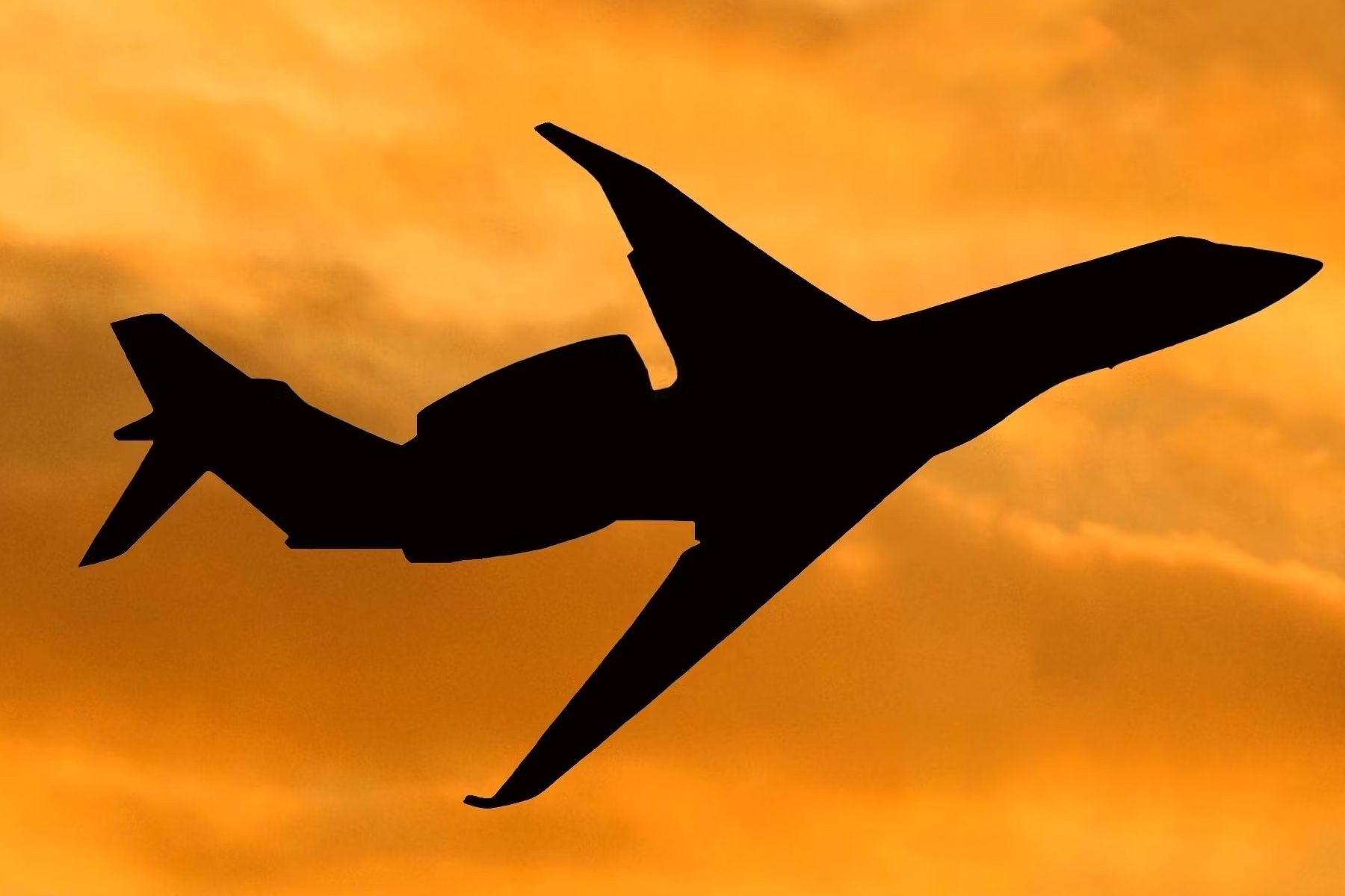 The silhouette of a private jet flying in the sky.
