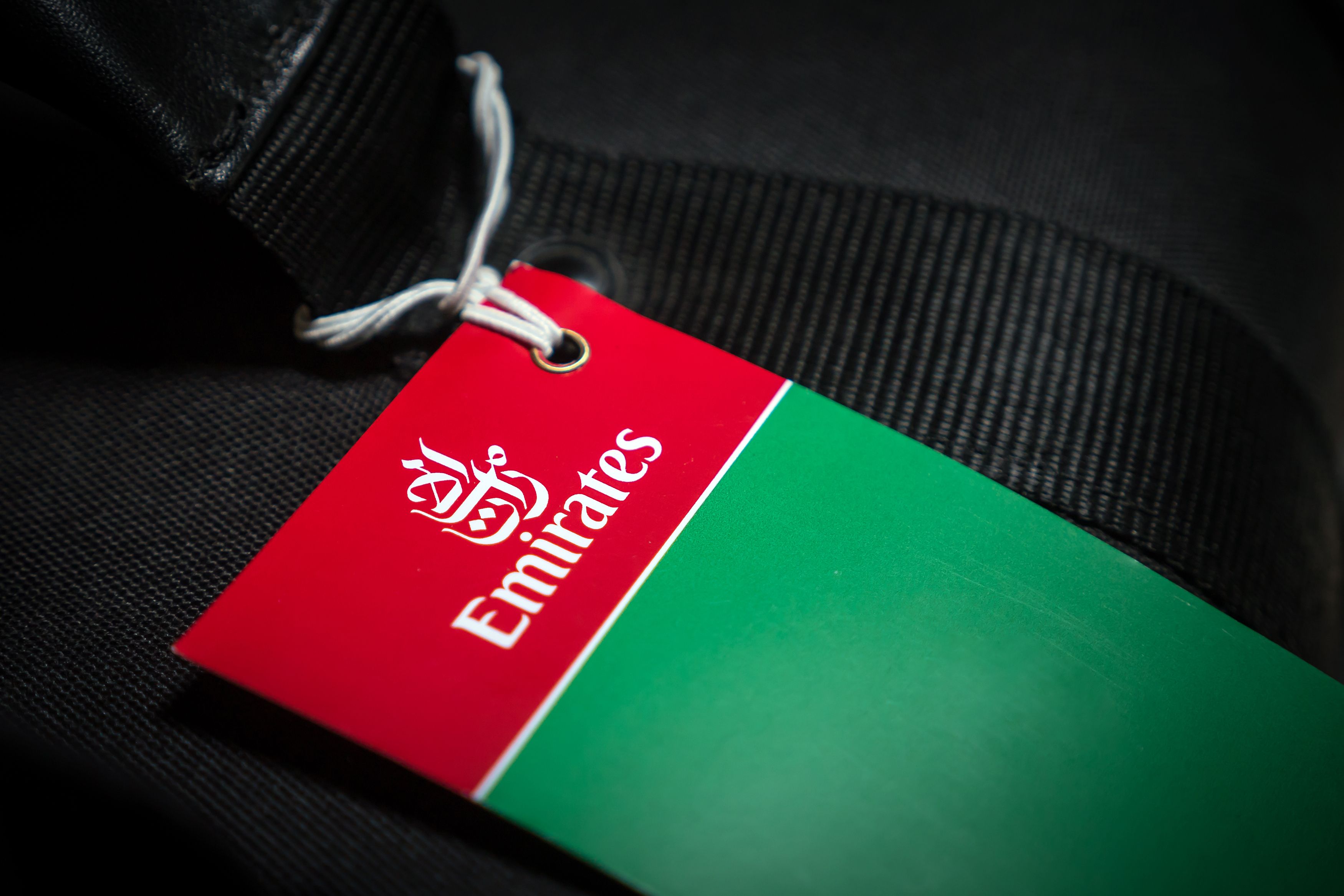 An Emirates baggage tag attached to a suitcase.