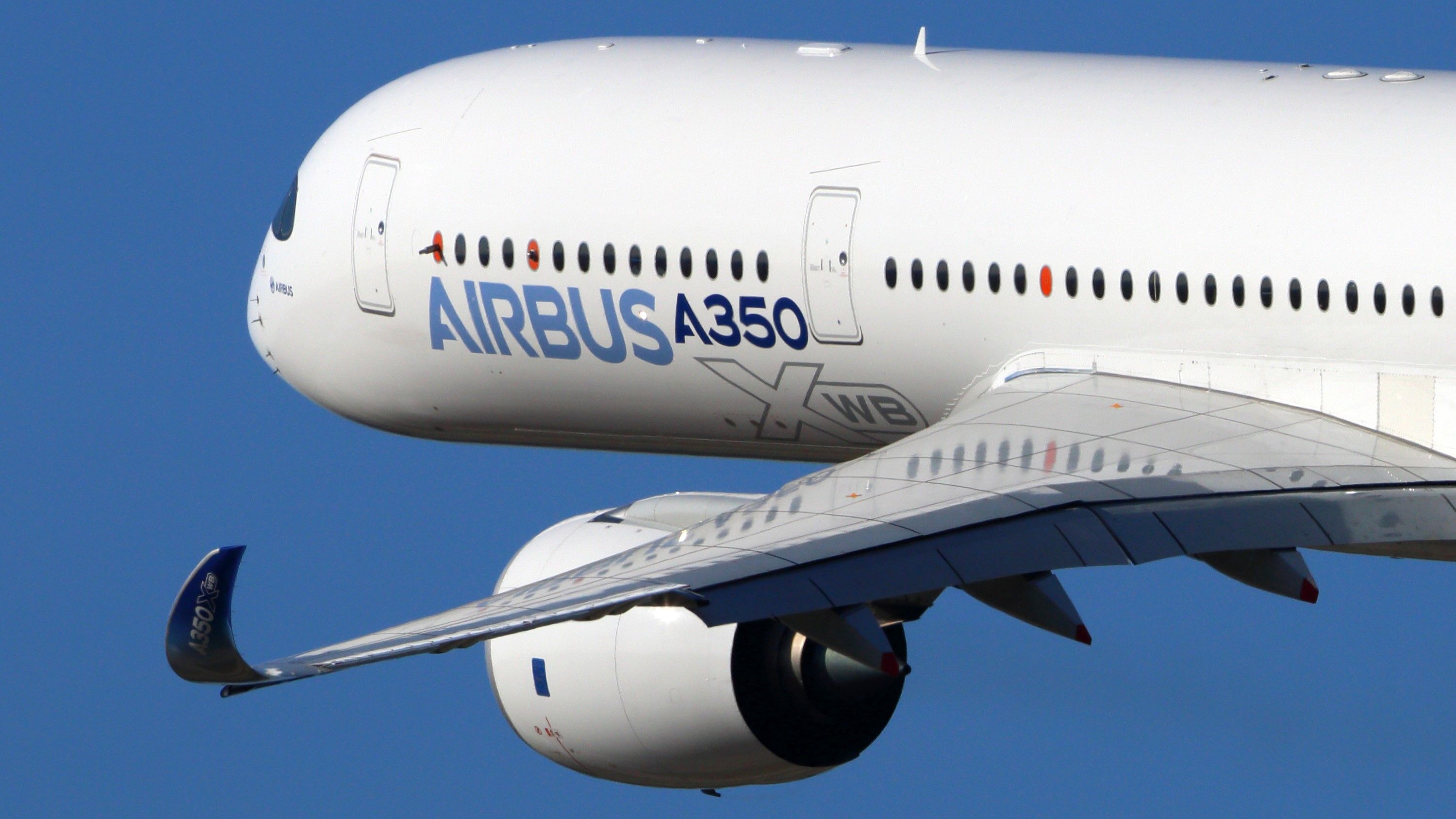 A closeup of the front half of an Airbus A350XWB in the sky.