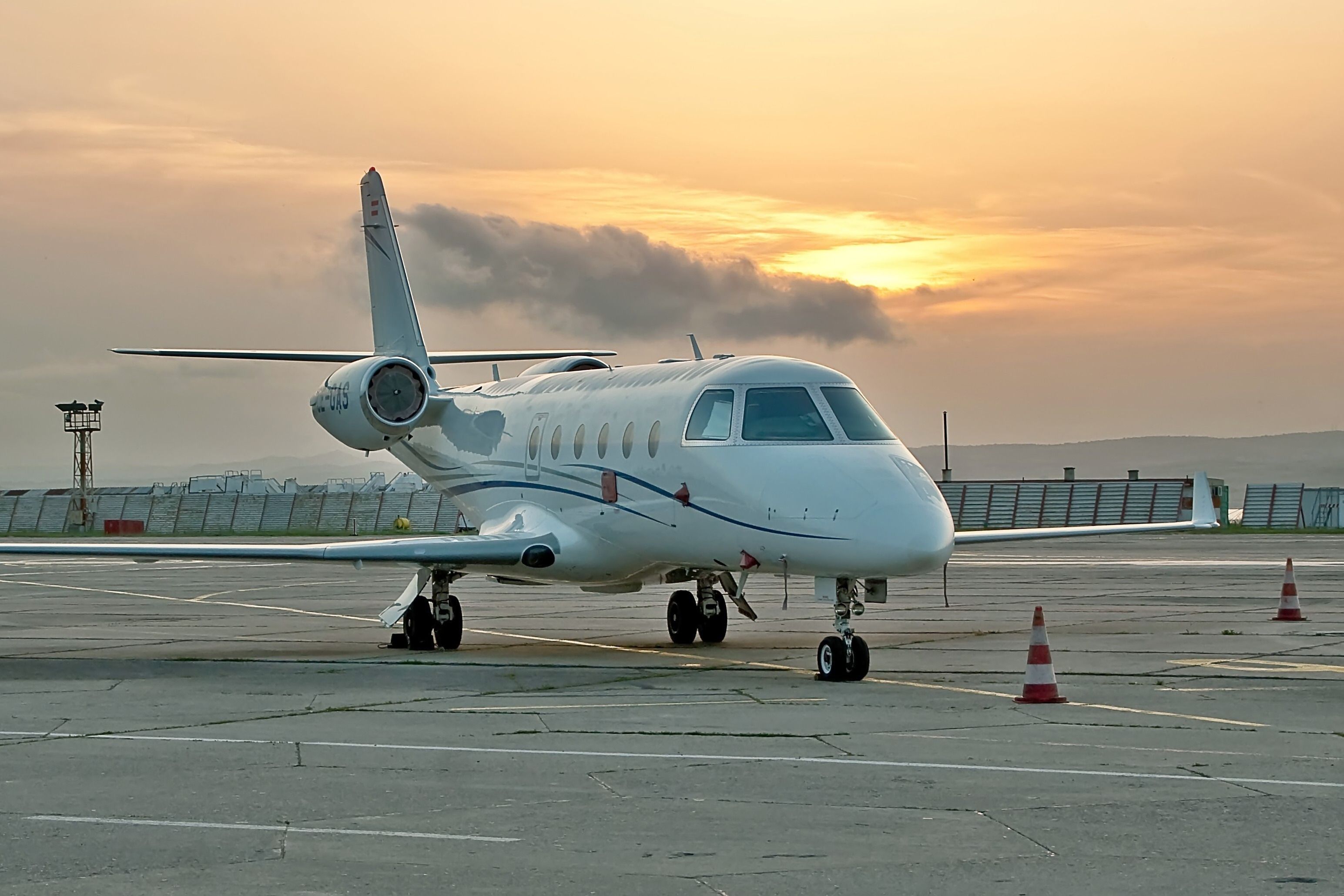 A Gulfstream G150 parked on an airport apron during sunset.