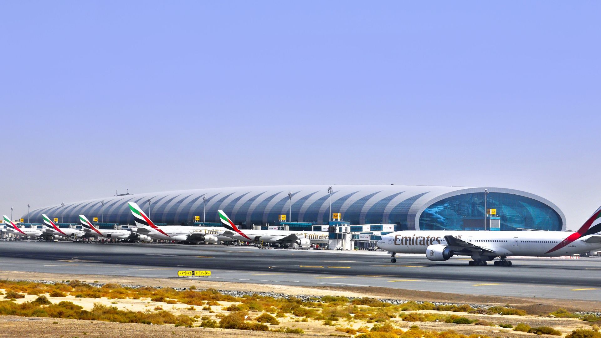 A Panoramic view of Dubai International Airport, with several Emirates aircraft on the apron.