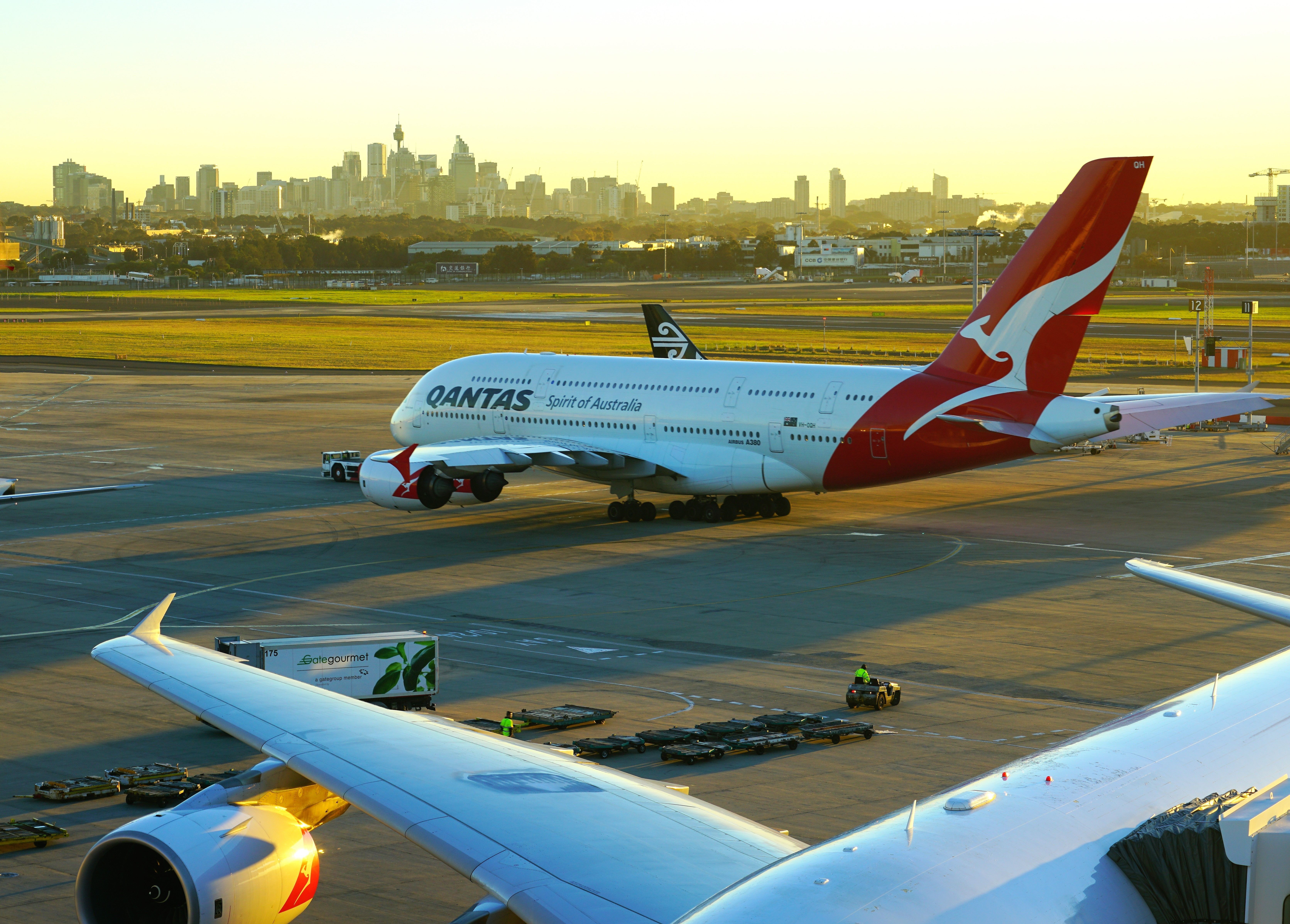 A Qantas Airbus A380 being pushed by a truck on an airport apron.