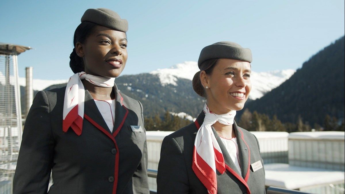 Two VistaJet cabin crew members with snow-capped mountains in the background.