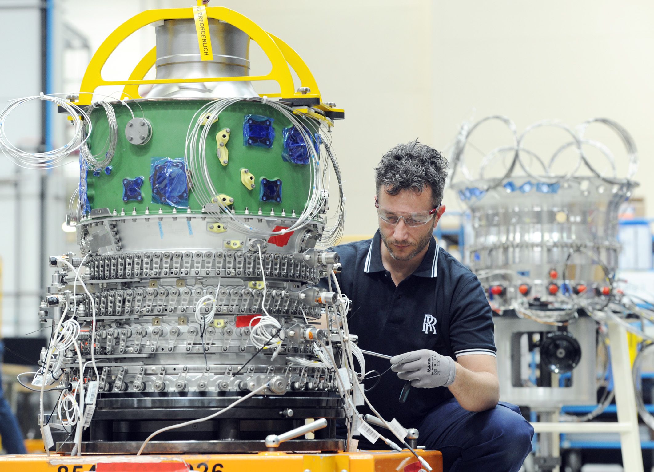 A Rolls-Royce Pearl 15 Engine being maintanined by an engineer.