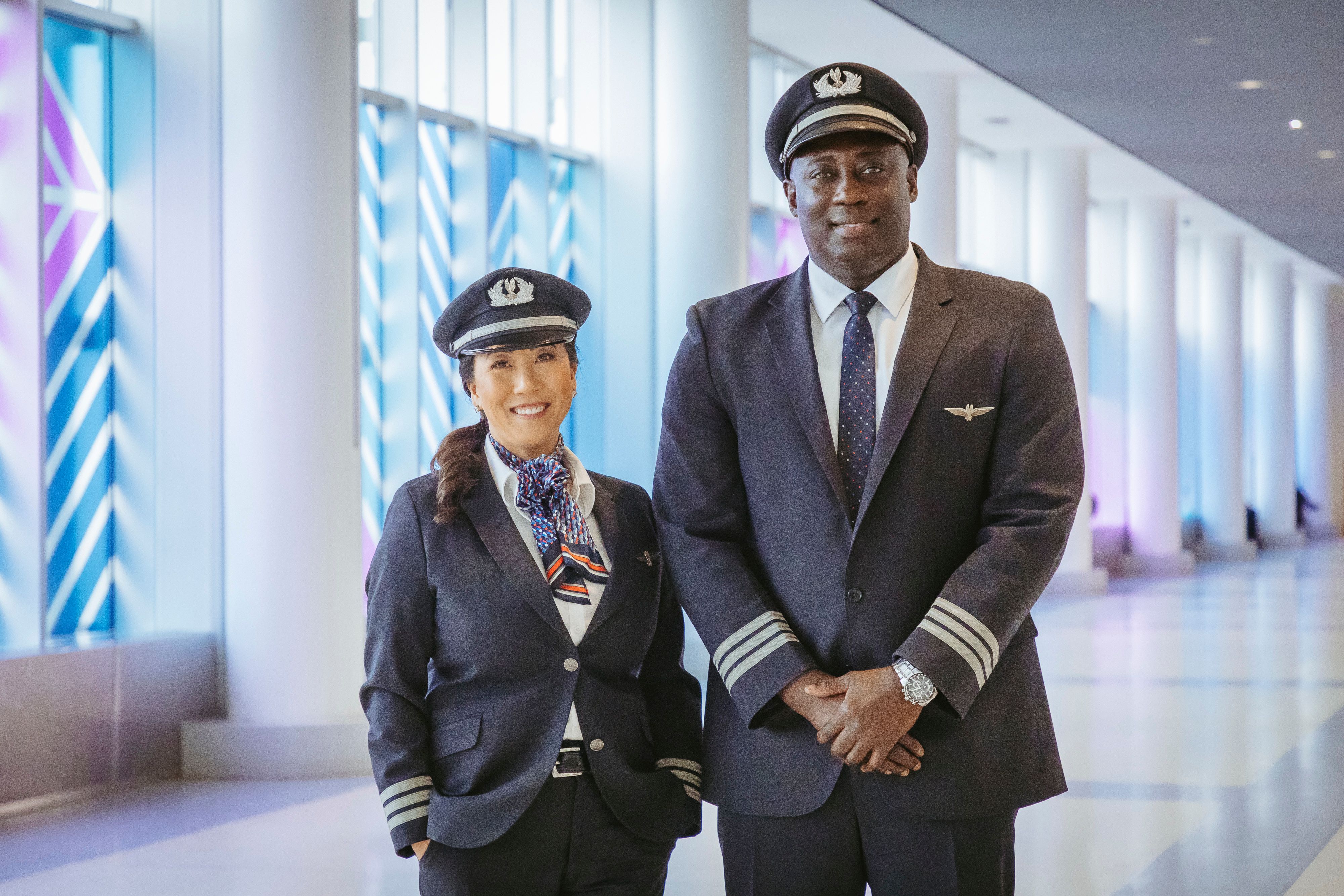 Two American Airlines pilots standing in an airport terminal.