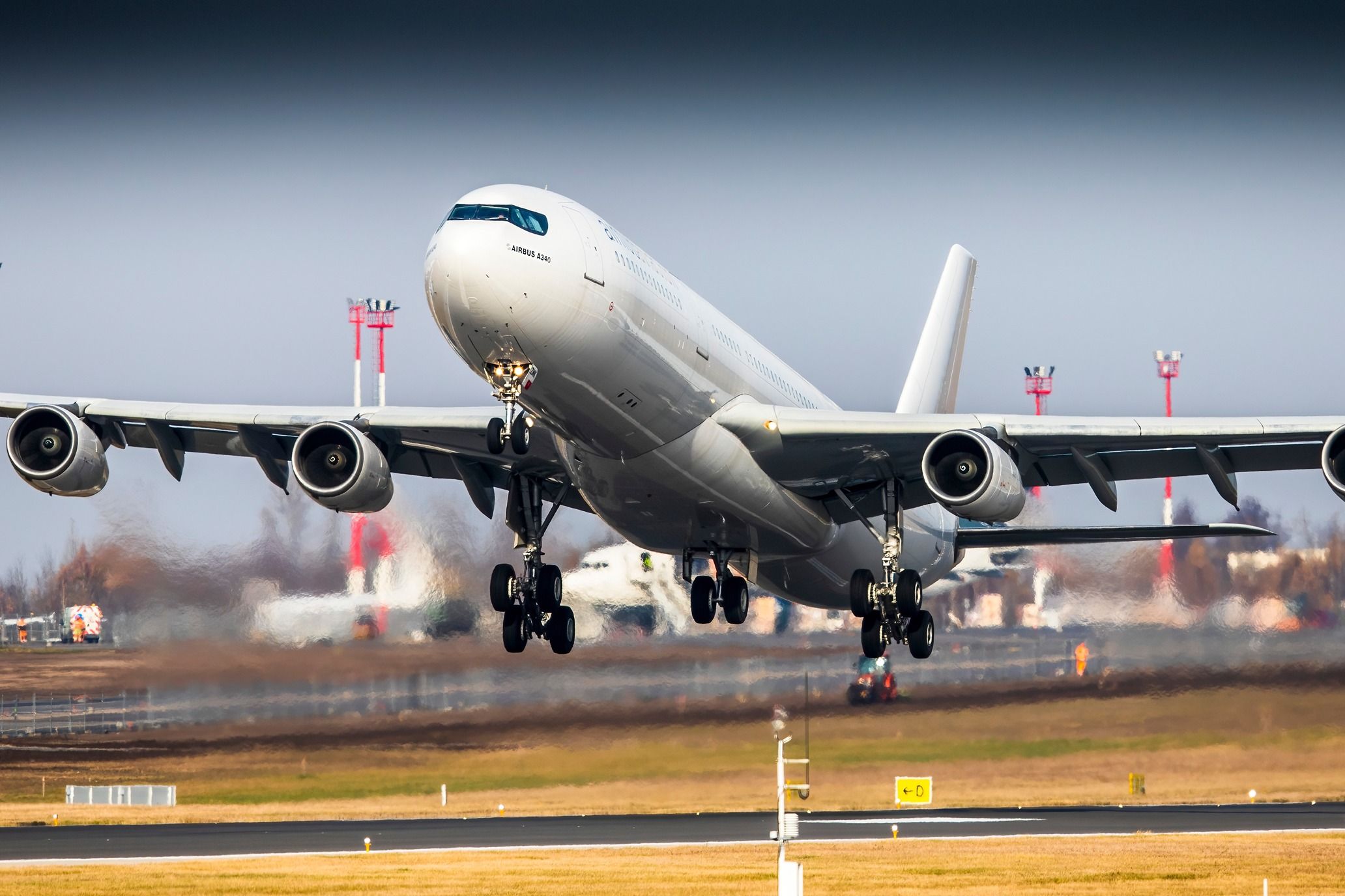 An All-white Airbus A340 taking off from an airport.