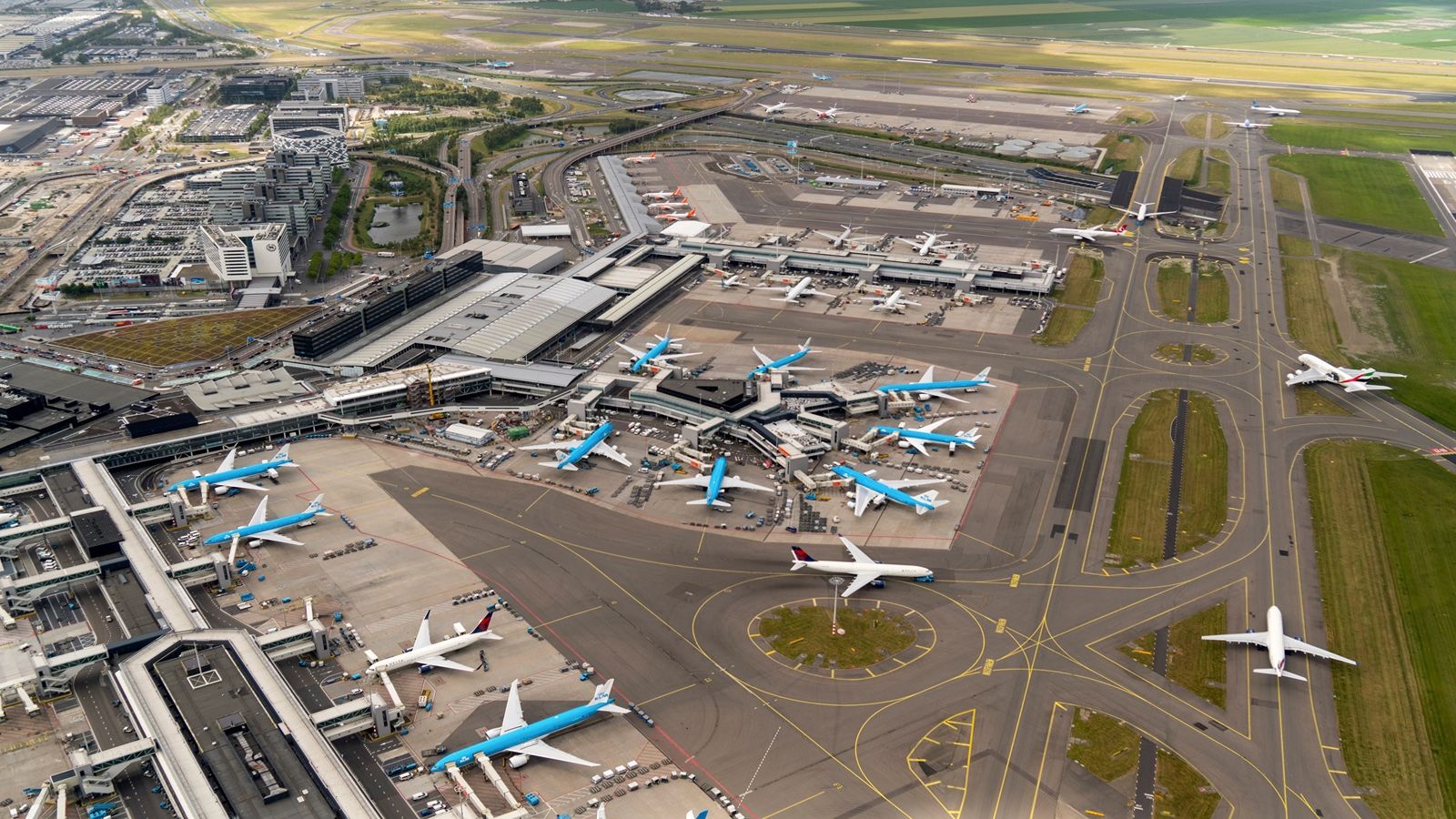An aerial view of Amsterdam Schiphol airport with many KLM and other aircraft on the apron.