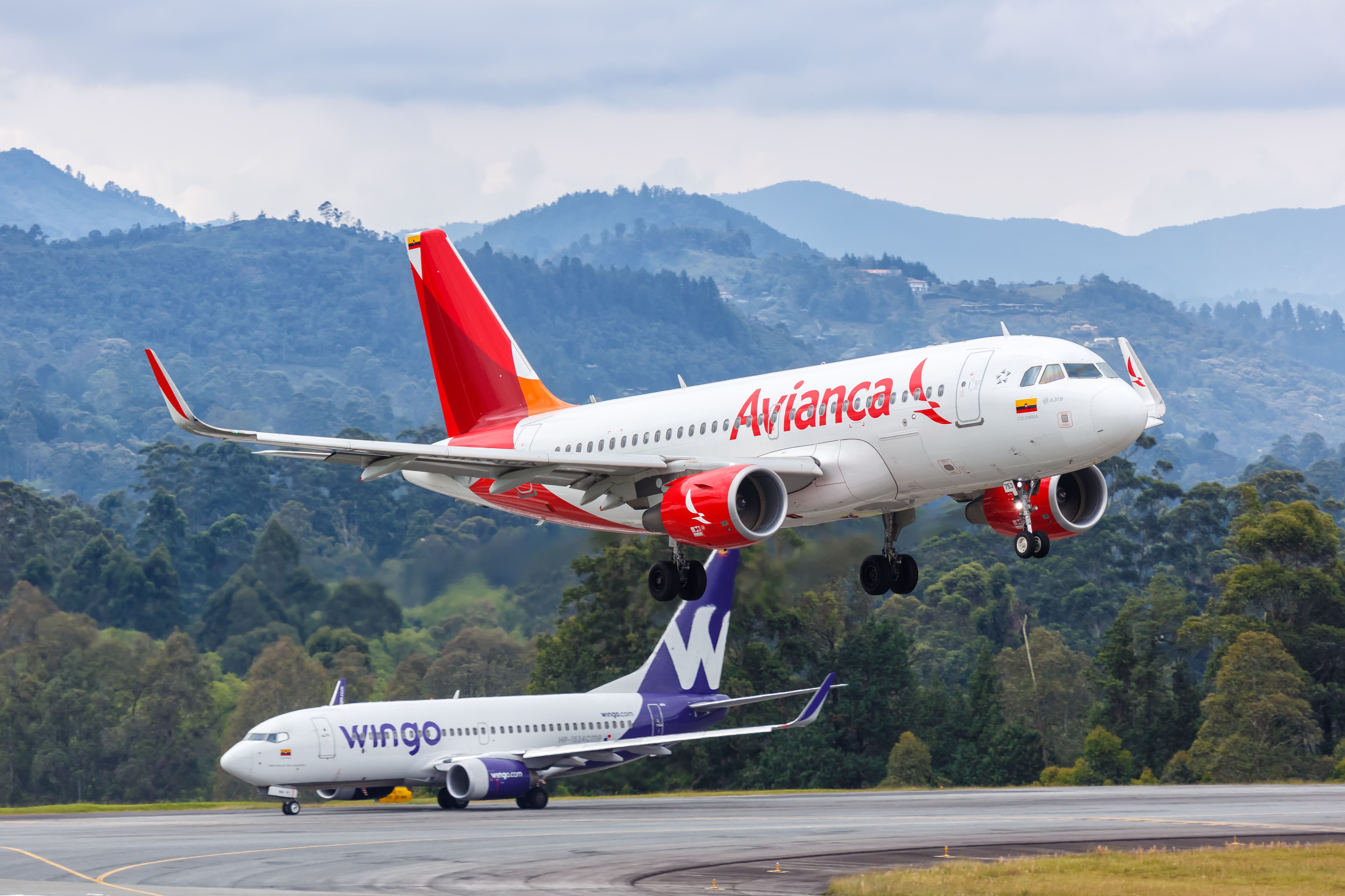 An Avianca aircraft landing and in the back a Wingo Boeing 737 