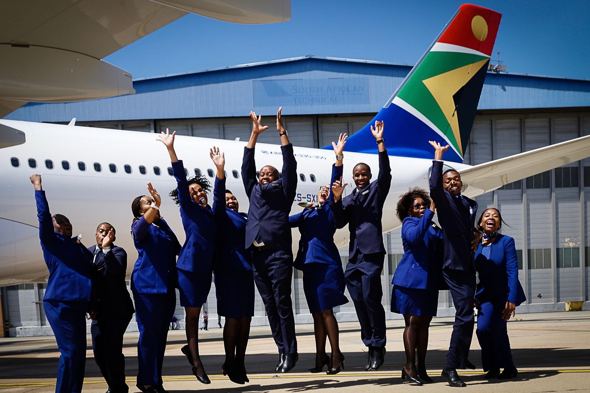 Several South African Airways Cabin Crew standing beside an Airbus A330.