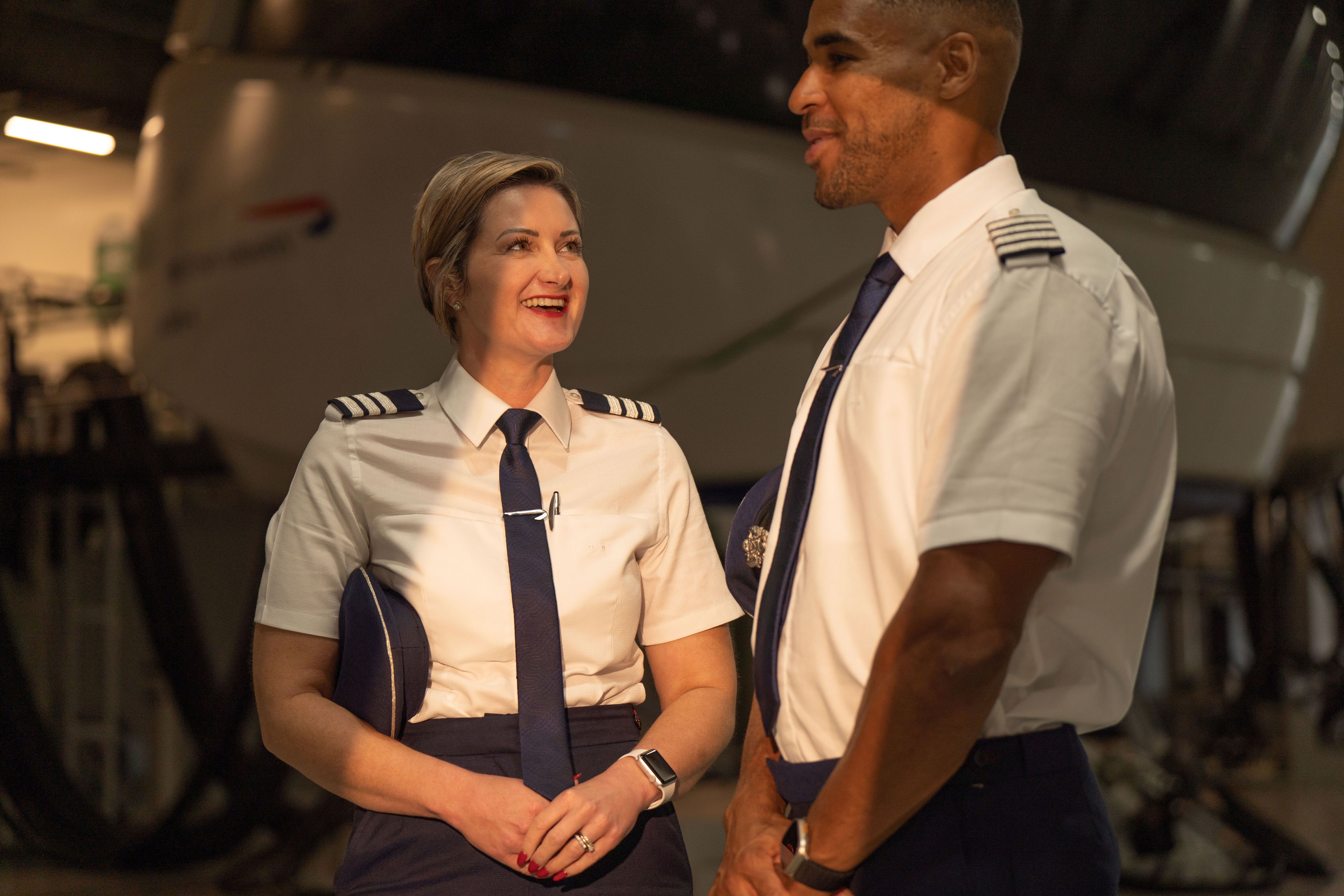 Two British Airways pilots standing near an aircraft simulator. 