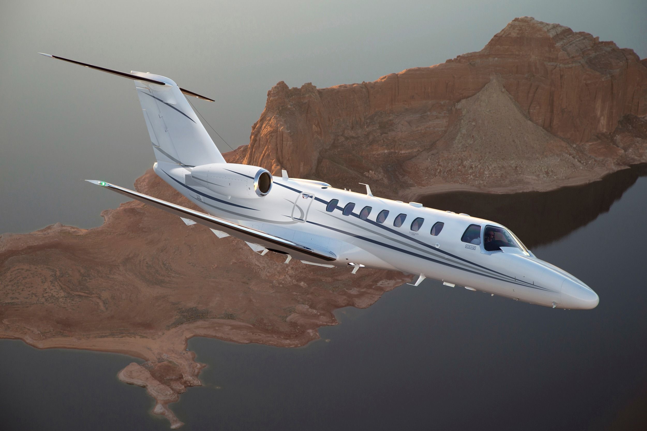 A render of a Cessna Citation CJ3 Gen2 flying over a rock formation near water.