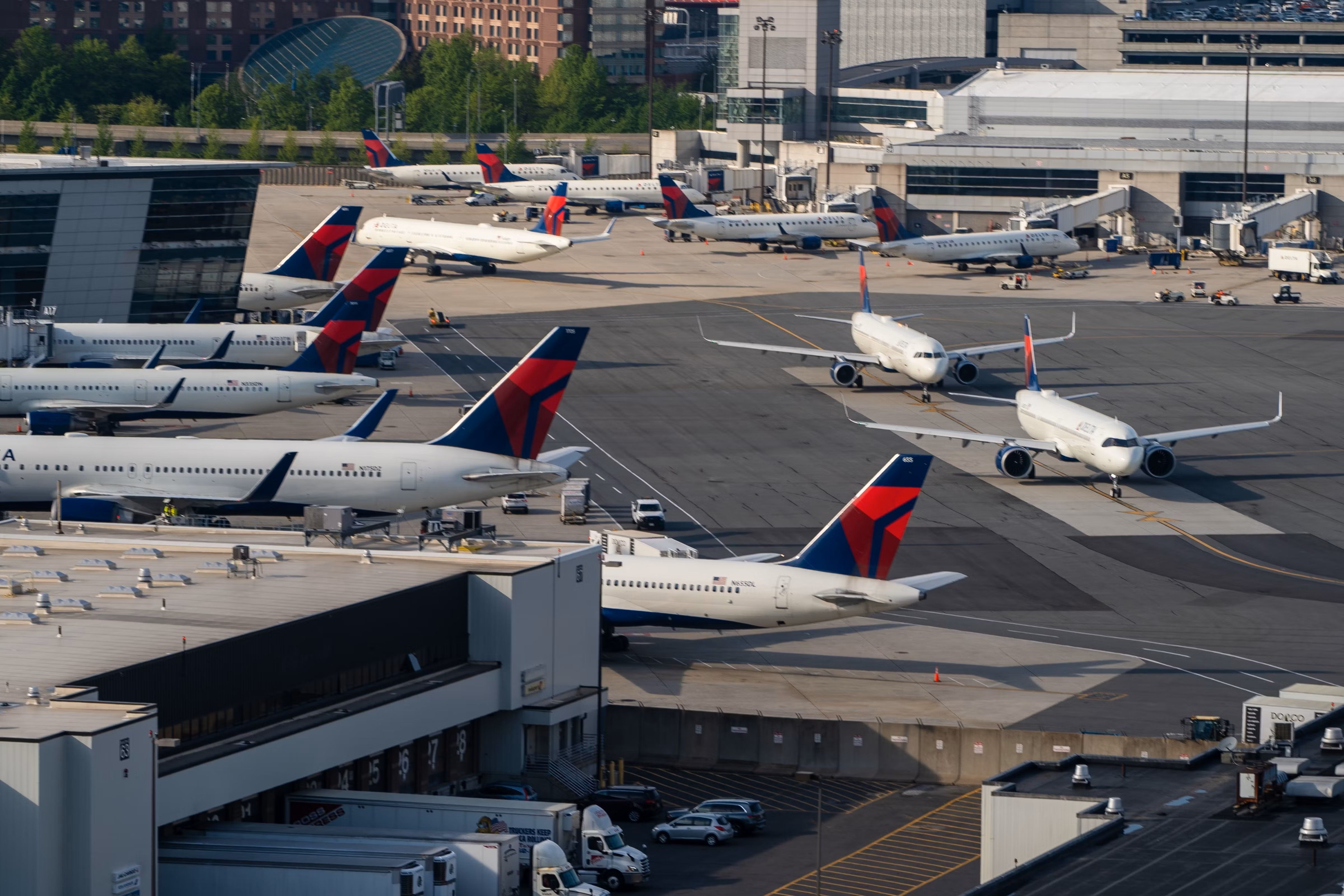 Several Delta Airlines planes stand on the apron of Boston Logan Airport.