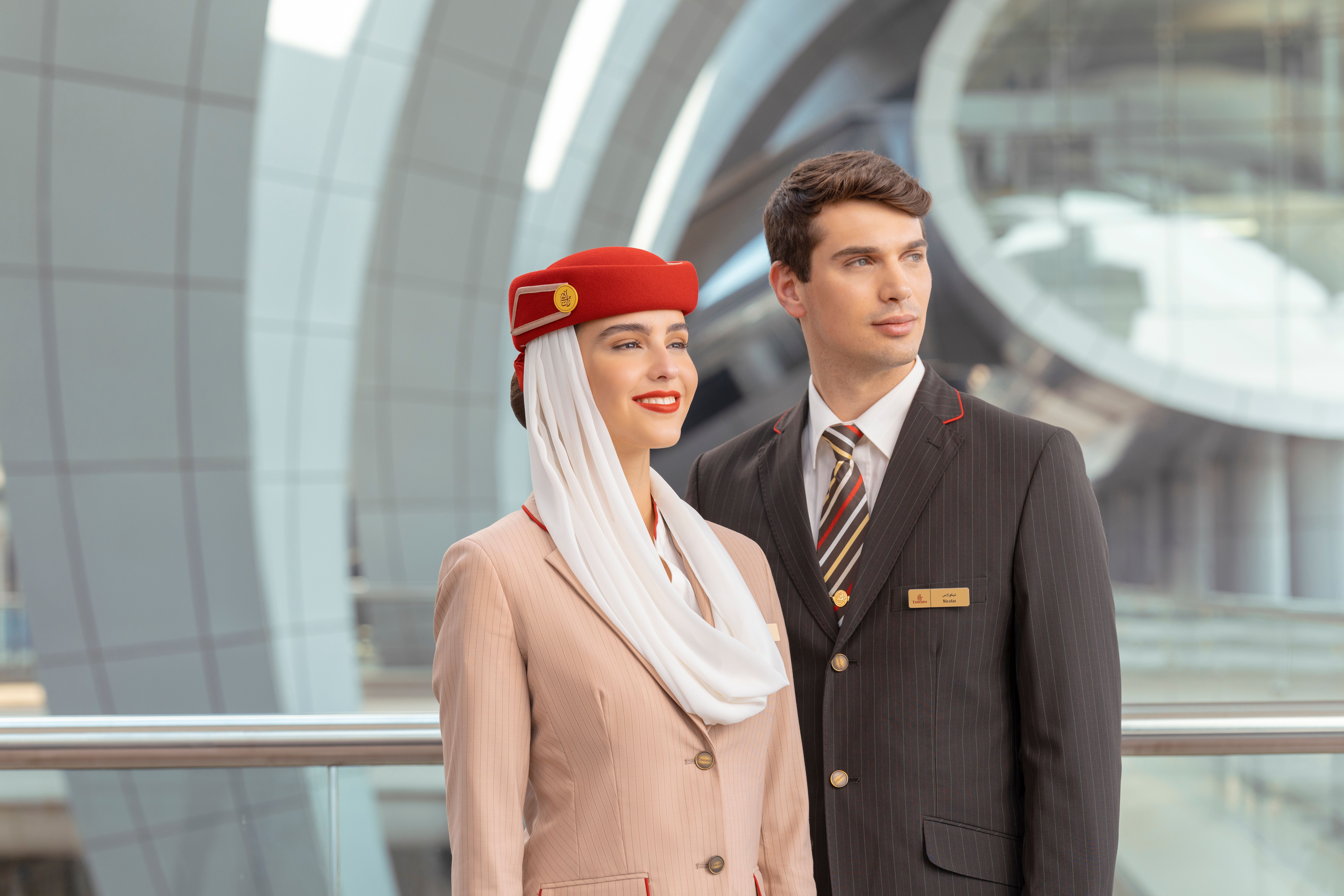 Male and female Emirates cabin crew members posing for a camera.