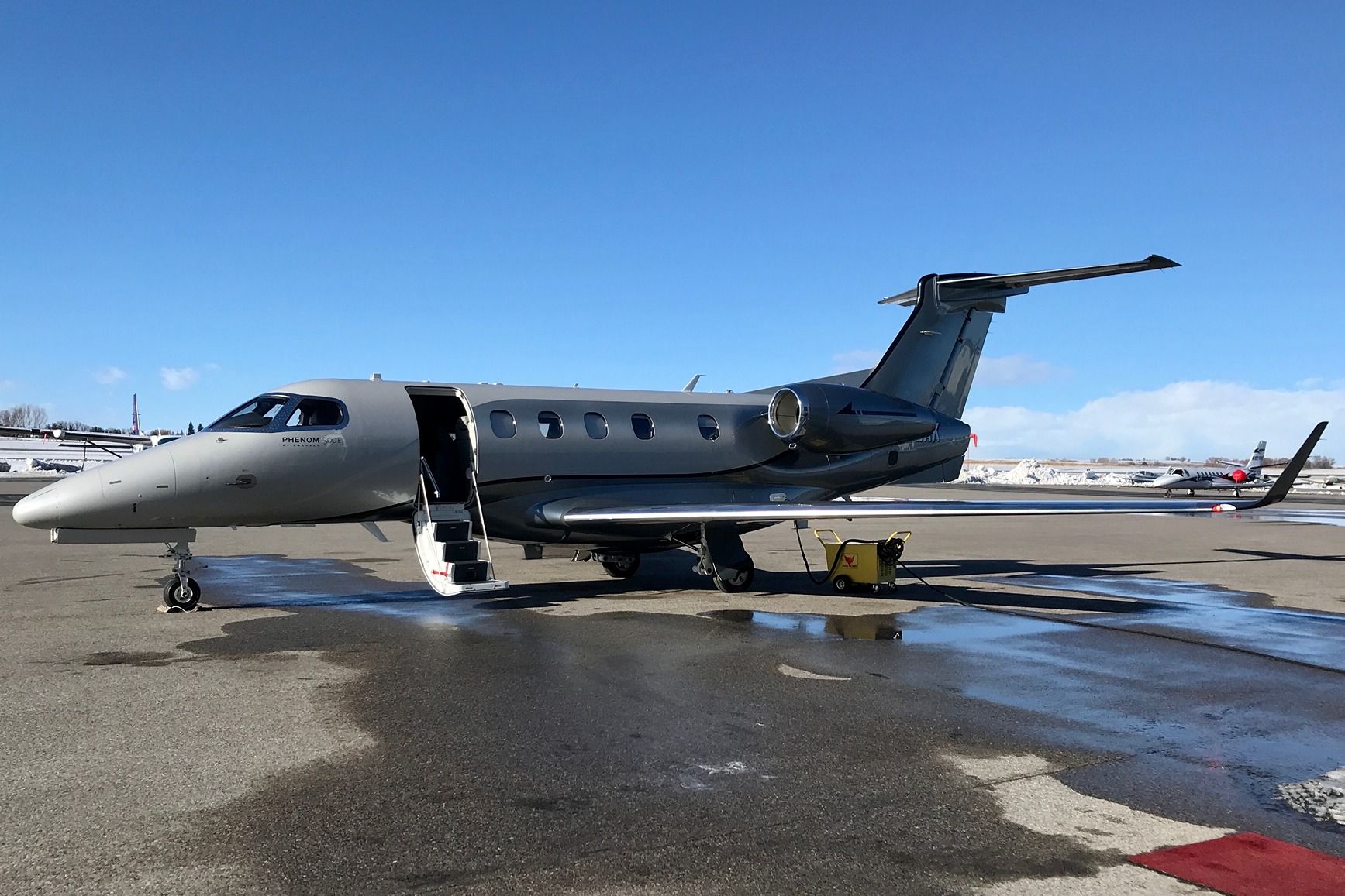 An Embraer Phenom 300E parked on the airport apron.
