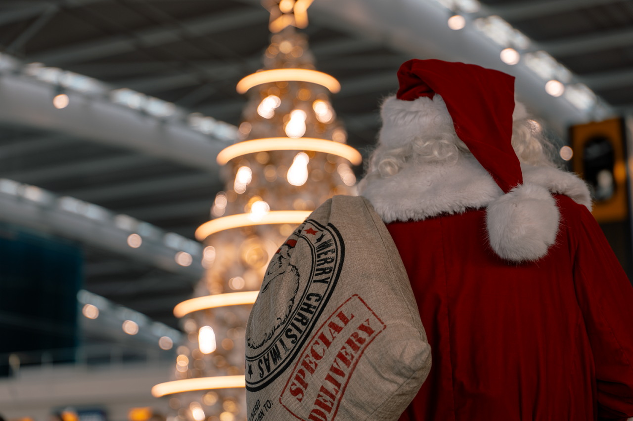 Santa standing in front of a christmas tree at Heathrow Airport.
