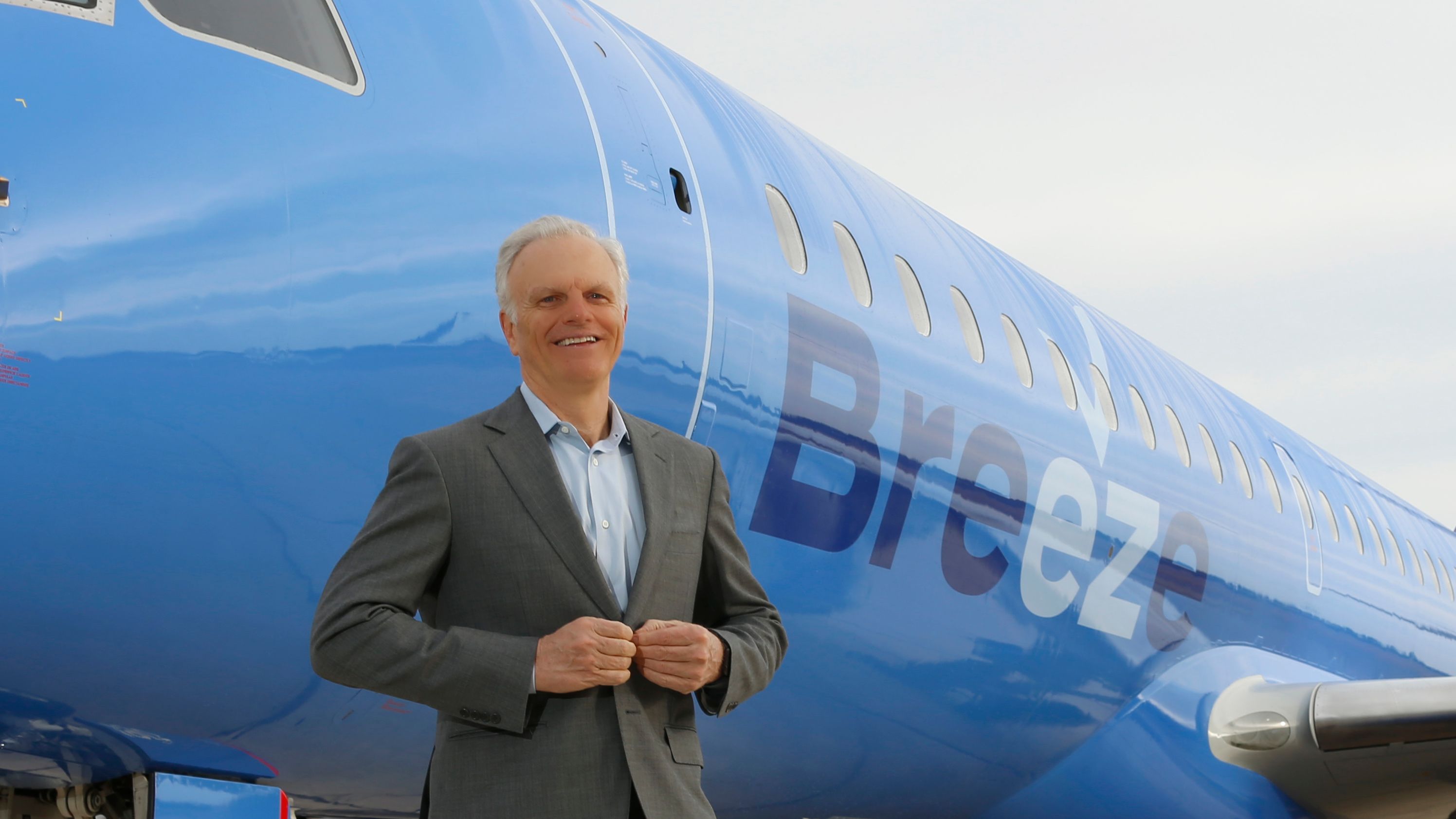 David Neeleman standing in front of a Breeze Airways aircraft.